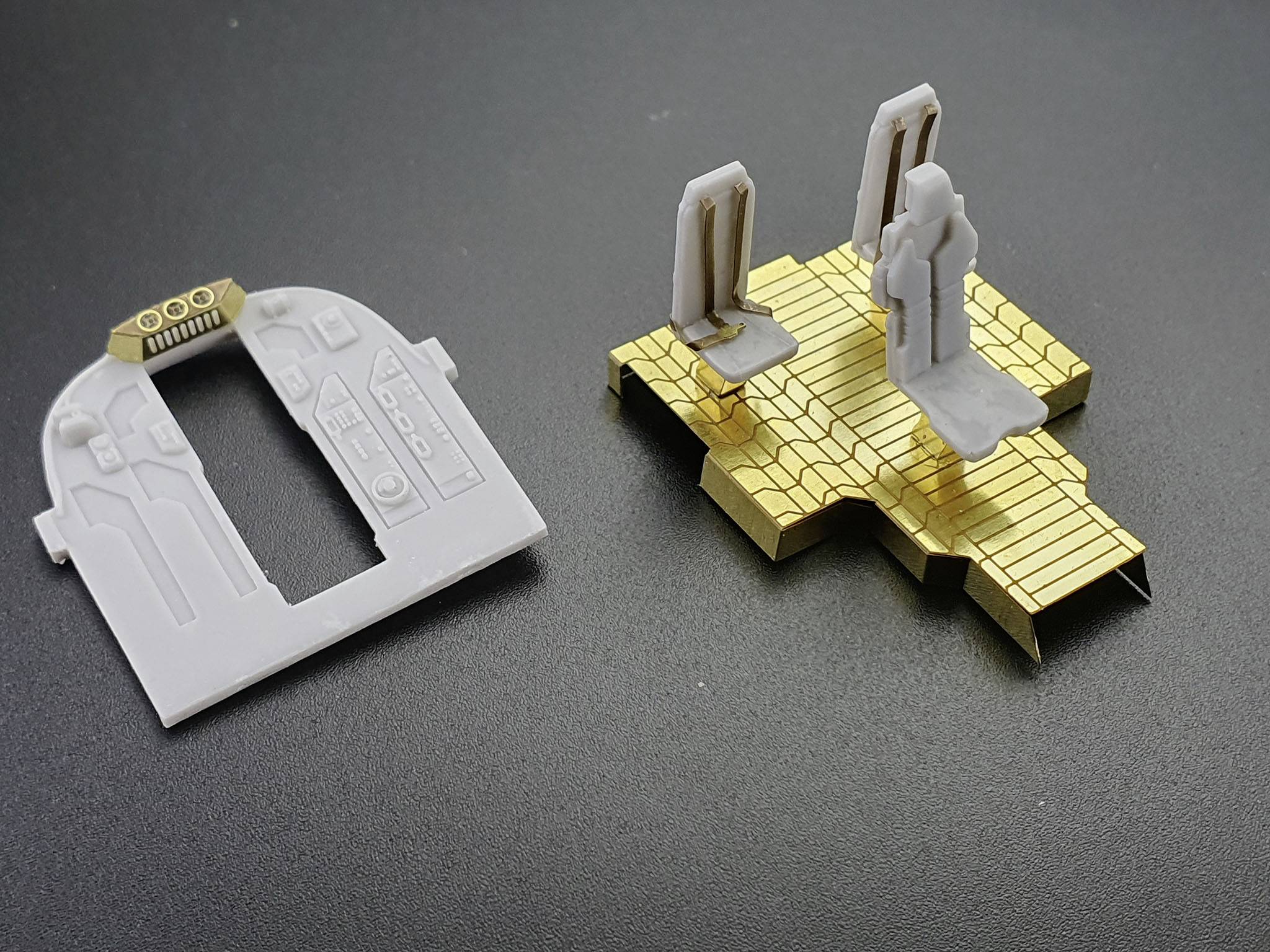 Weiße und goldene Modellteile auf schwarzem Hintergrund, möglicherweise für ein architektonisches oder technisches Modell.