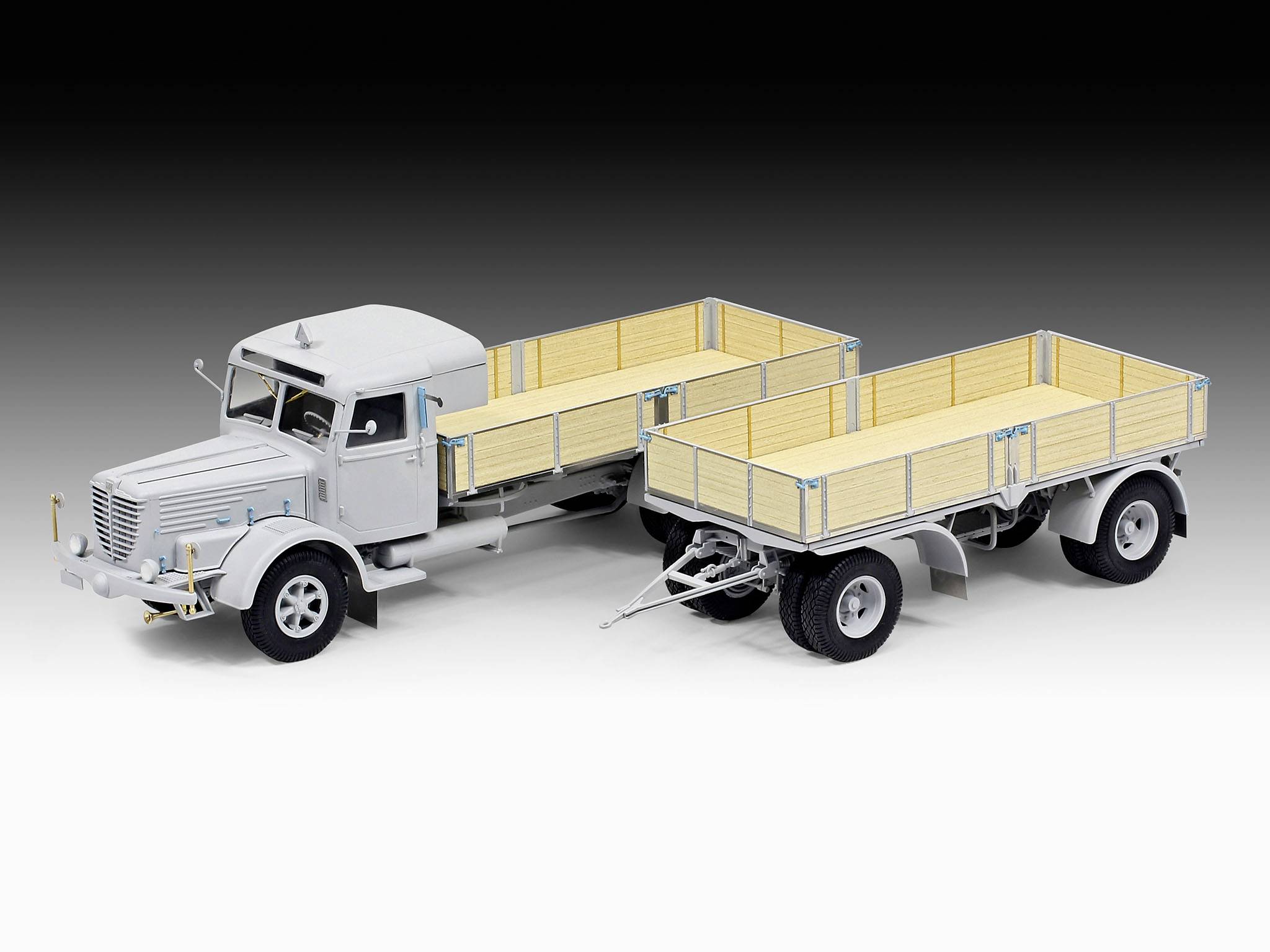 Ein grau-weißer Modell-LKW mit zwei offenen Anhängern aus Holz zeigt Details eines Lastwagens mit Ladekapazität.