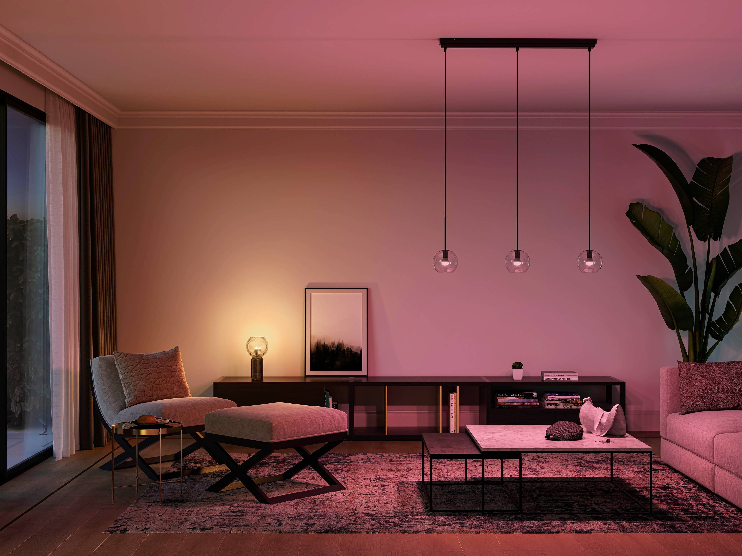 Ein modernes Wohnzimmer mit gedämpftem rosa Licht, grauen Möbeln, Pflanzen und einem gemütlichen Sessel neben einem Beistelltisch.