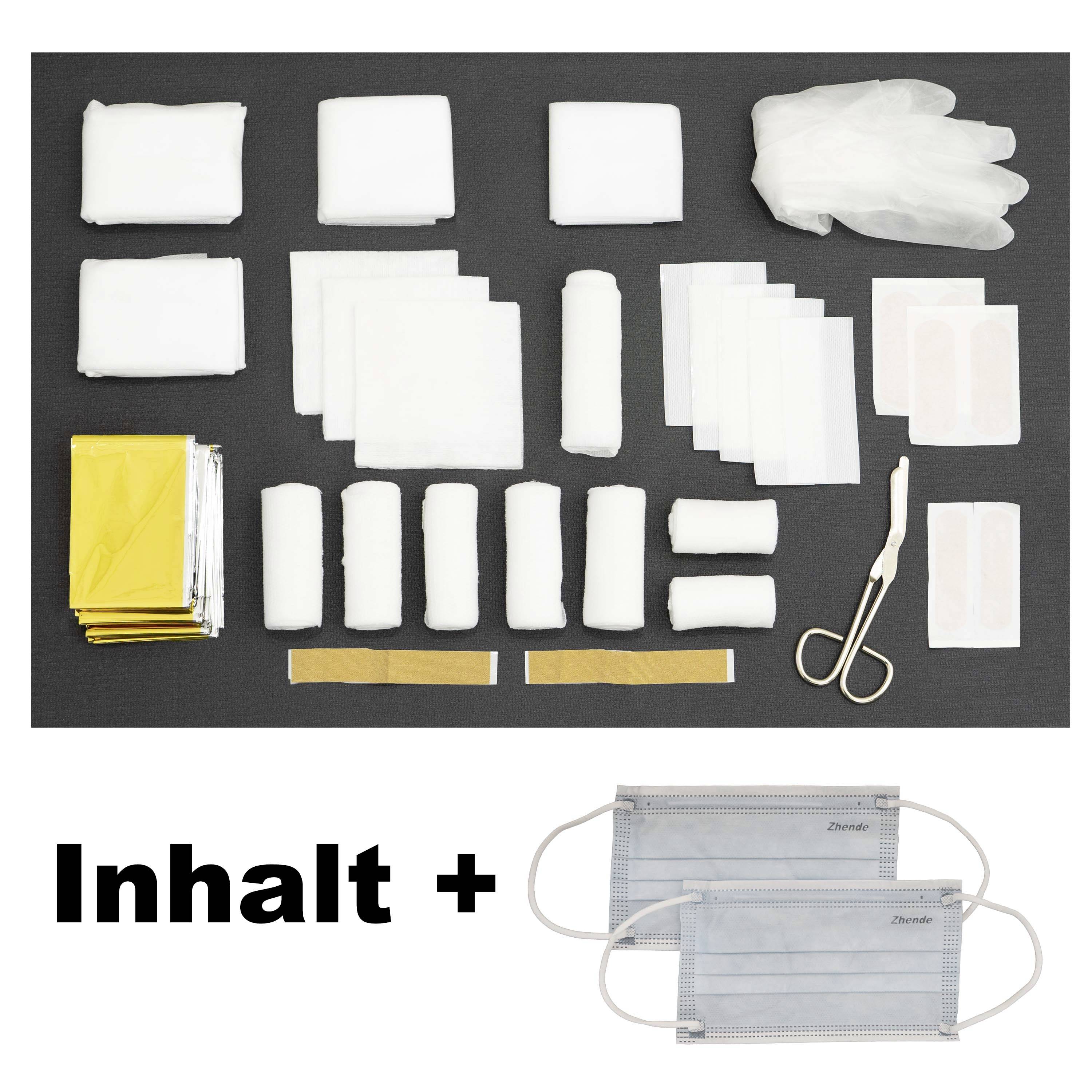 Ein Erste-Hilfe-Set mit Verbänden, Gaze, Pflastern, Schere, Handschuhen und Masken liegt auf einem dunklen Hintergrund.