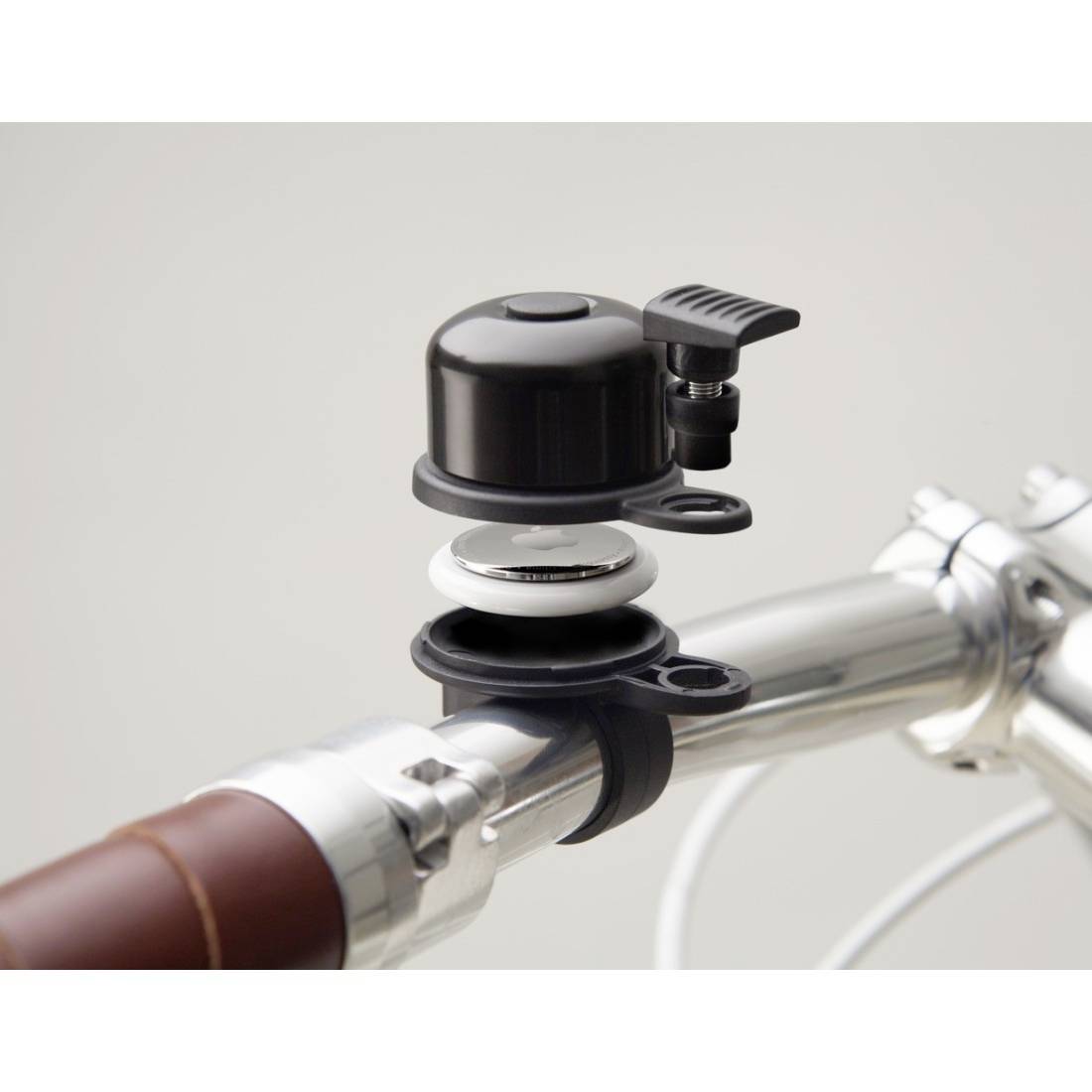 Fahrradklingel, montiert auf einem Fahrradlenker aus Metall. Holzgriff rechts im Bild, Klingel ist schwarz mit Druckknopf.