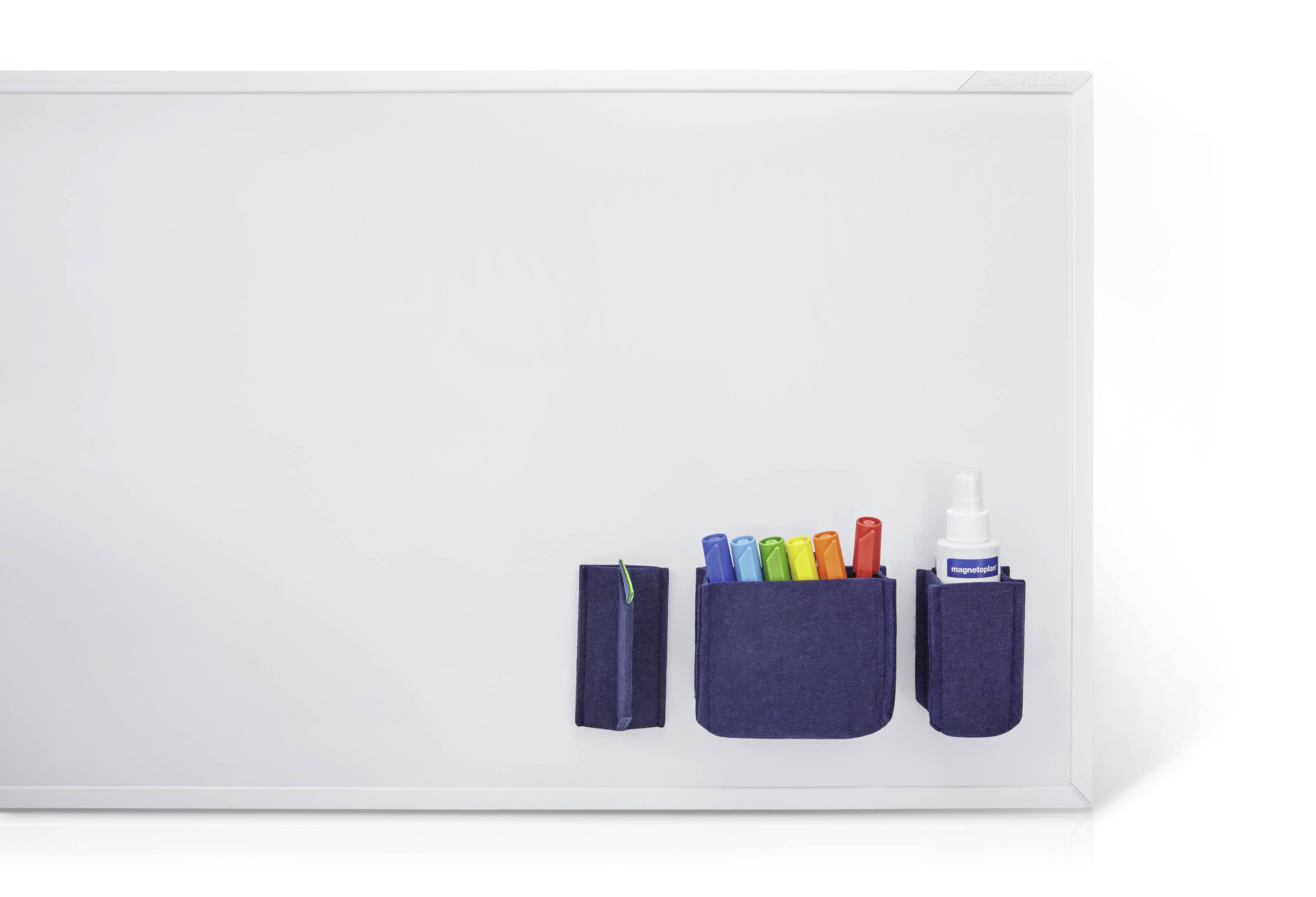 Ein leeres Whiteboard mit Stiftehalter, gefüllt mit farbigen Markern, und einem Reinigungsmittel in einer Flasche, an der rechten Seite.