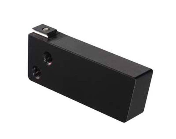 Rechteckiger, schwarzer Metallblock mit zwei kleinen Löchern an der Seite und einem hervorstehenden Stift oben. Dient industriellen Zwecken.