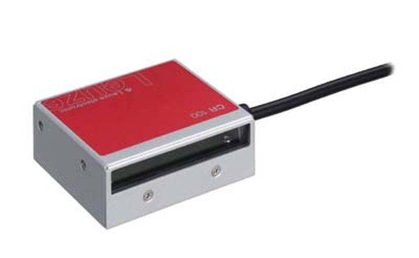 Ein quadratisches, elektronisches Gerät mit roter Oberfläche und Kabel auf der rechten Seite. Es scheint ein Scanner oder Sensor zu sein.