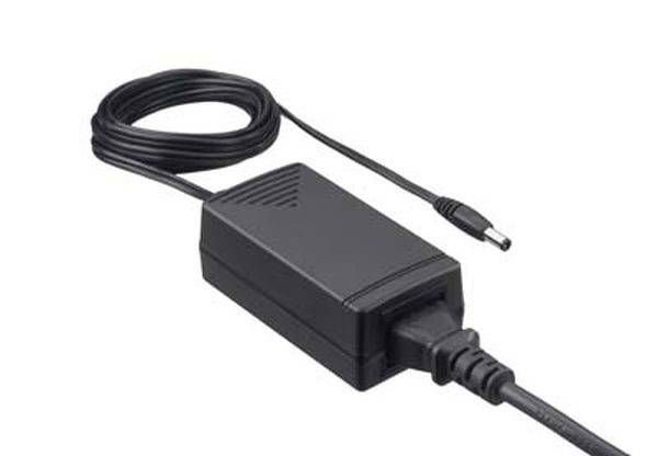 Ein schwarzes Netzteil mit spiralförmig aufgerolltem Kabel und Stecker, geeignet zur Stromversorgung von elektronischen Geräten.