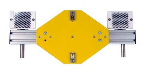 Gelbes quadratisches Geräteschild mit zwei rechteckigen metallischen Komponenten an den Seiten, montiert auf einer Schiene.