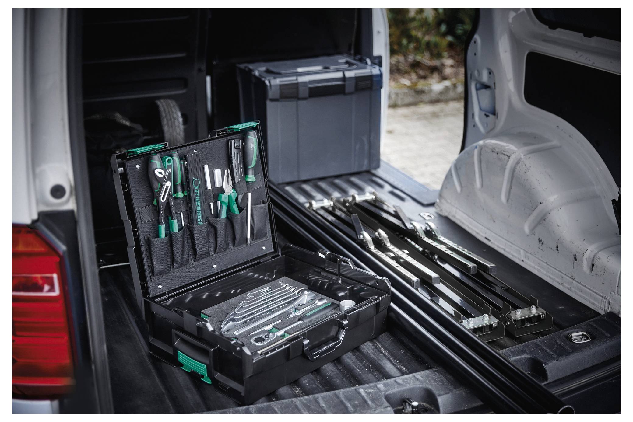 Werkzeugkasten offen in der Ladefläche eines Fahrzeugs, mit ordentlich angeordneten Werkzeugen und Ausrüstungen auf einer ausgeklappten Heckklappe.