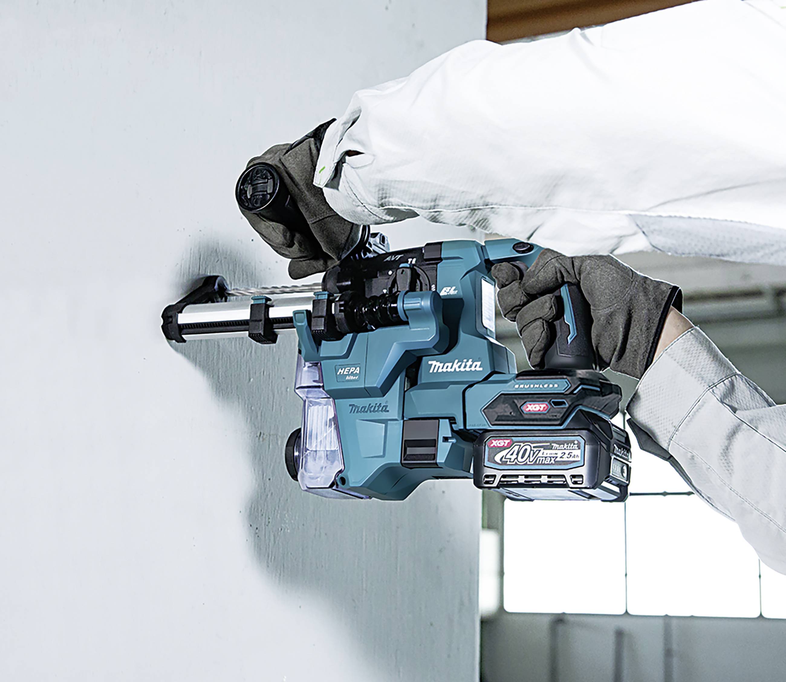 Bohrmaschine der Marke Makita bohrt in eine Betonwand. Ein Arbeiter hält das Gerät sicher fest. Die Umgebung wirkt industriell.