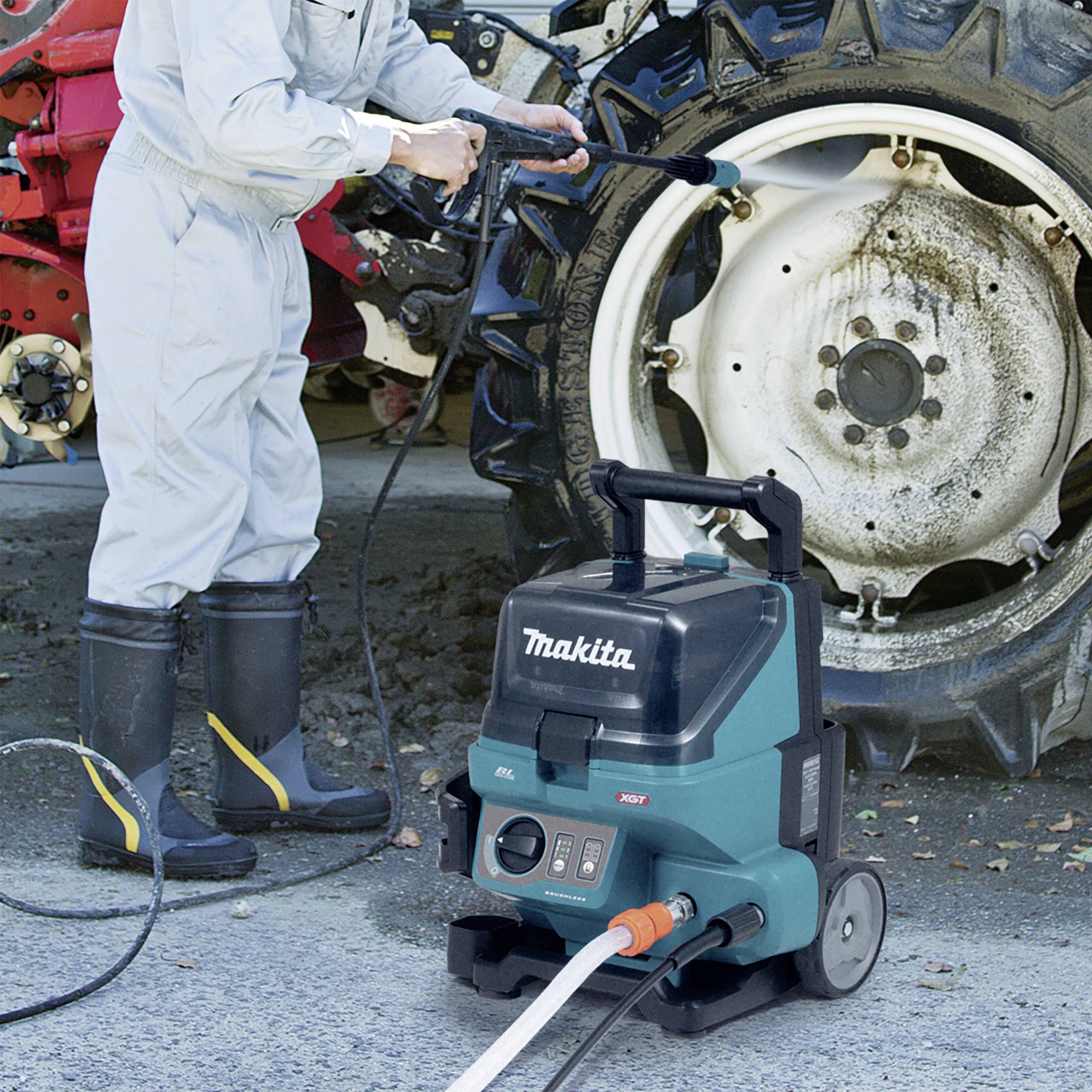 Eine Person reinigt mit einem Hochdruckreiniger einen großen Traktorreifen. Im Vordergrund steht ein Makita-Reinigungsgerät.