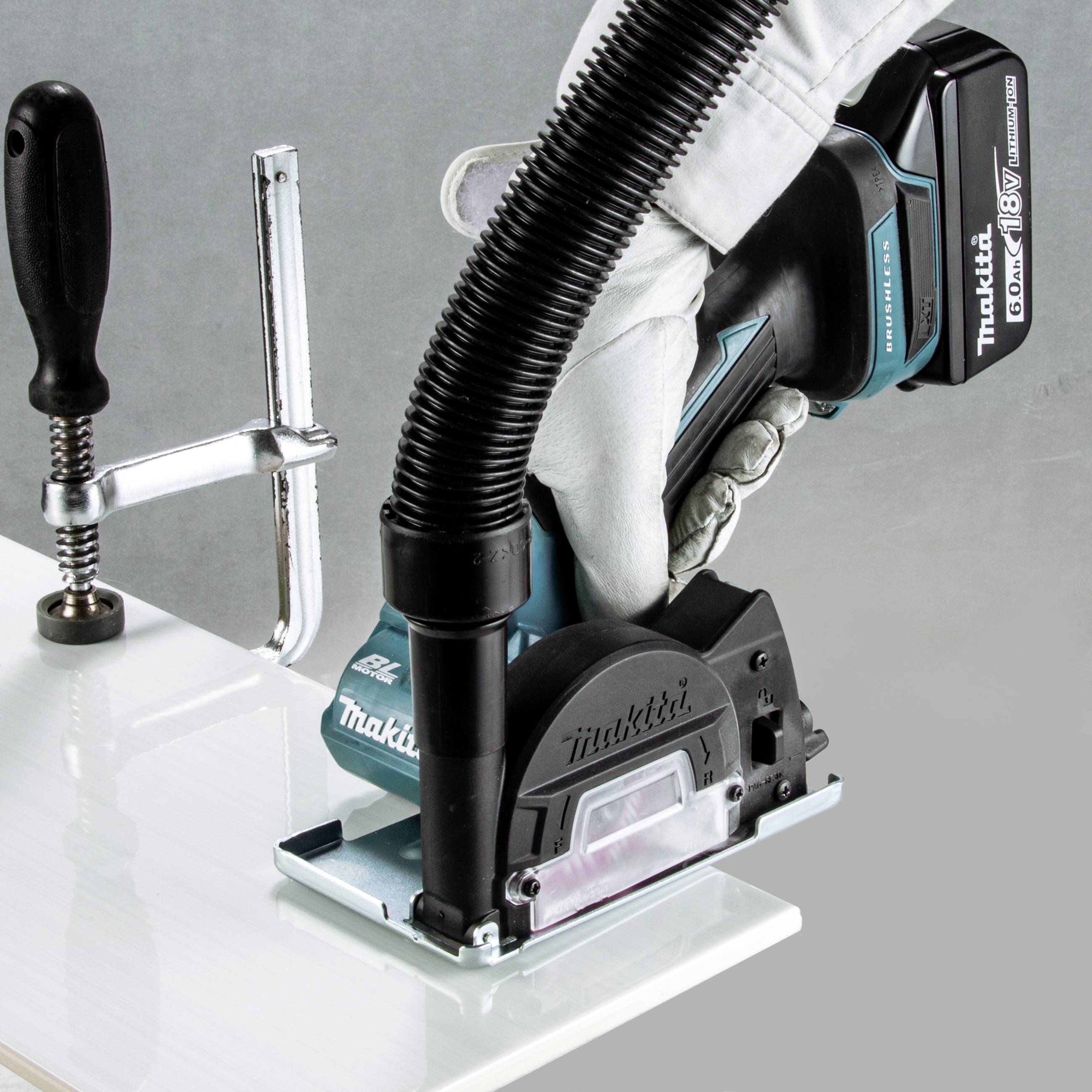 Eine Hand hält ein Makita-Elektrowerkzeug zum Schleifen eines auf einer Werkbank eingespannten Metallstücks.