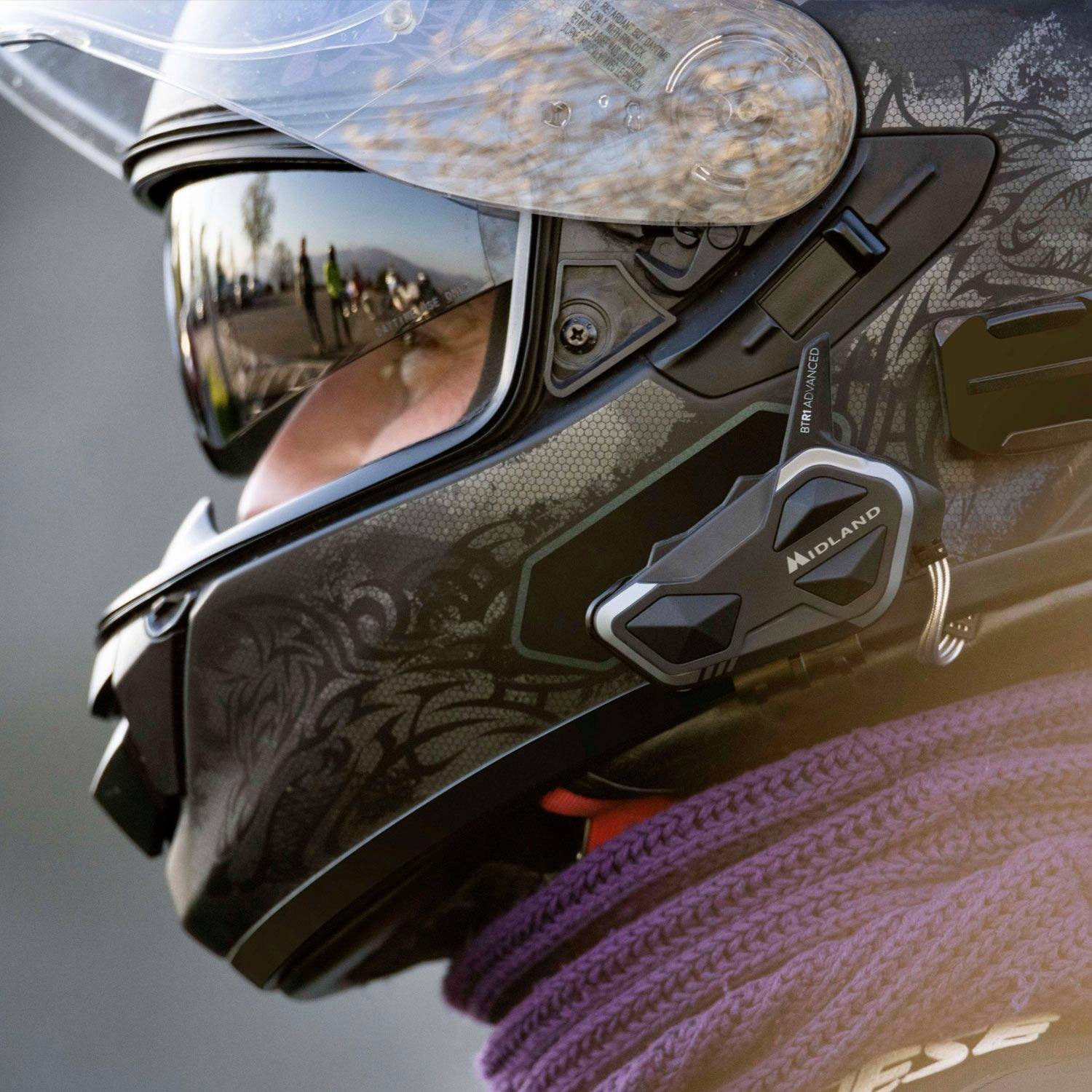 Motorradhelmfotografie mit geöffnetem Visier, zeigt komplexe Grafik und integriertes Kommunikationsgerät auf der Seite.