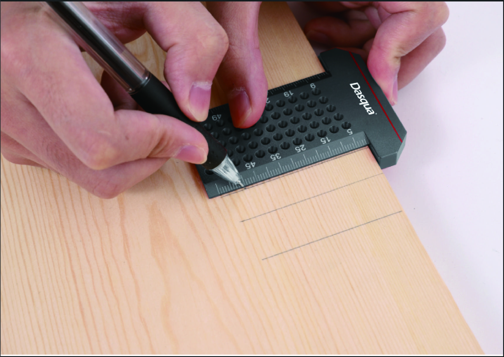 Eine Person markiert mit einem Stift und einem Lineal Maße auf einem Holzbrett für einen präzisen Schnitt.