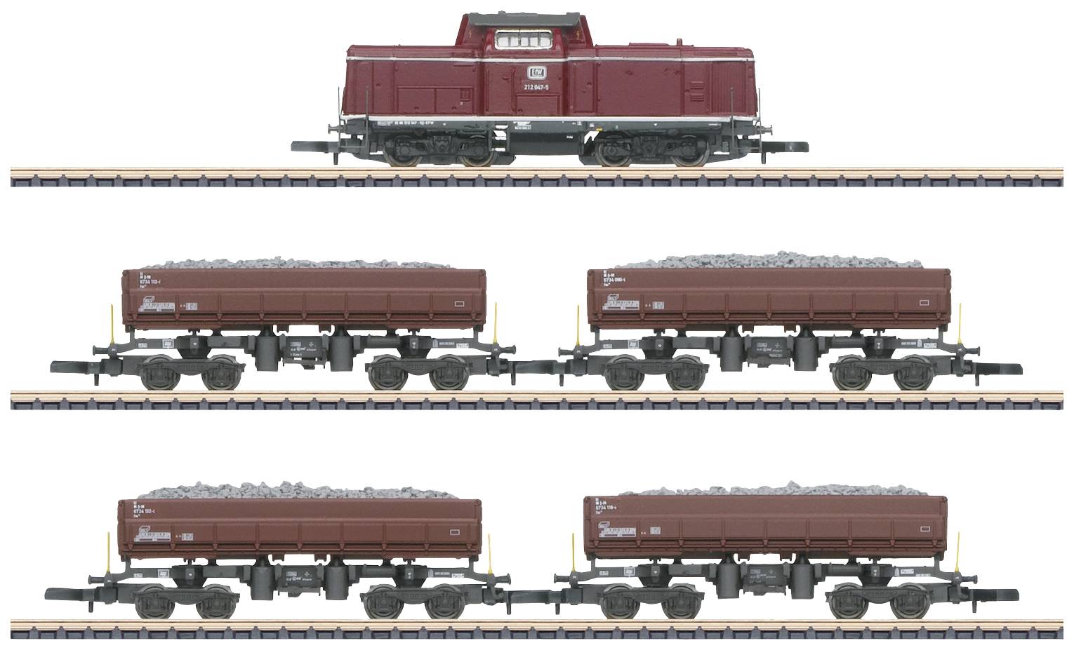 Ein roter Zug mit einer Lokomotive und vier mit Schotter beladenen Waggons steht auf einem Gleis.