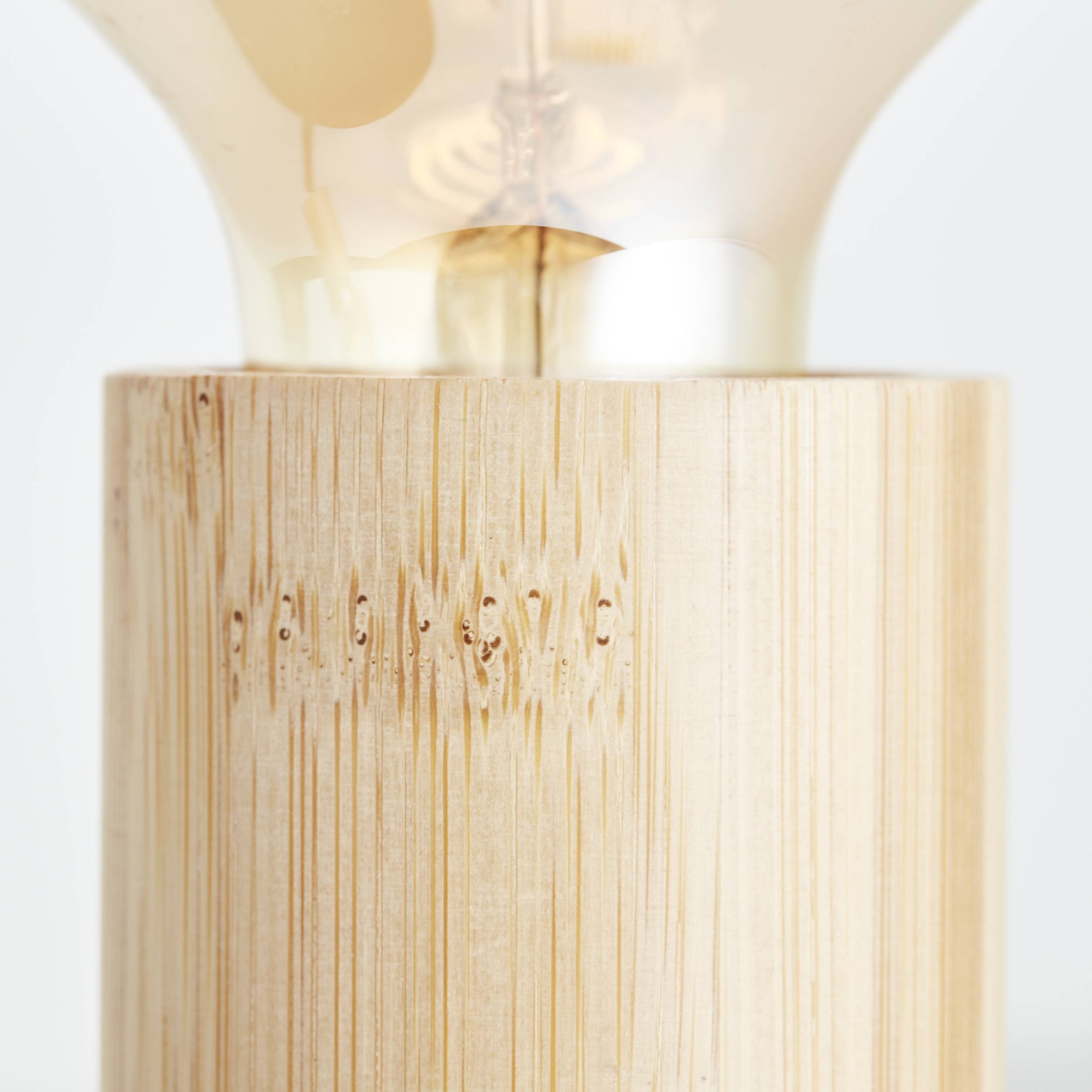 Nahaufnahme einer Holzlampe mit einem sichtbaren Teil der Glühbirne. Der Lampensockel besteht aus natürlichem, hellem Holz.
