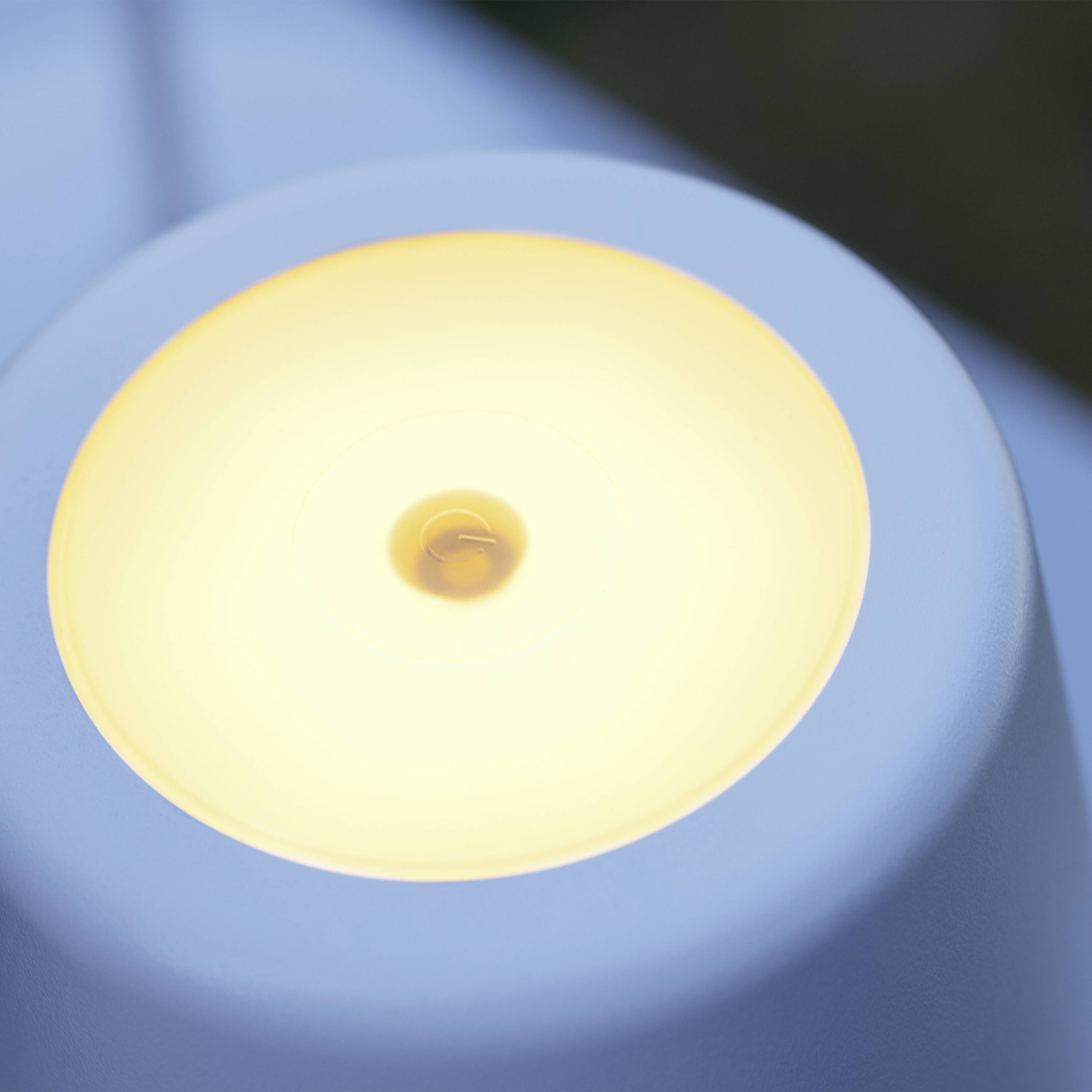 Eine Nahaufnahme einer runden, gelb leuchtenden Lampe in einem modernen Design, auf einem unscharfen Hintergrund.