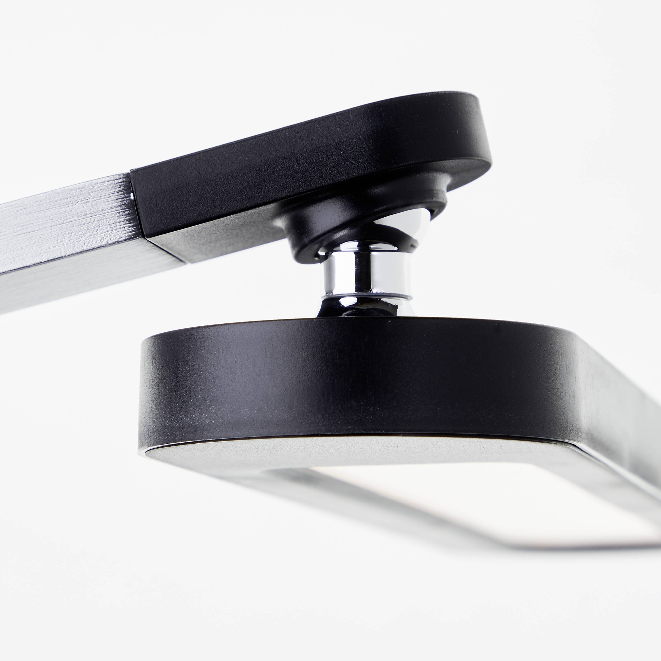 Detailaufnahme einer modernen, schwarzen Tischlampe mit schwenkbarem Arm und rechteckigem Lampenschirm im Minimalist-Stil.