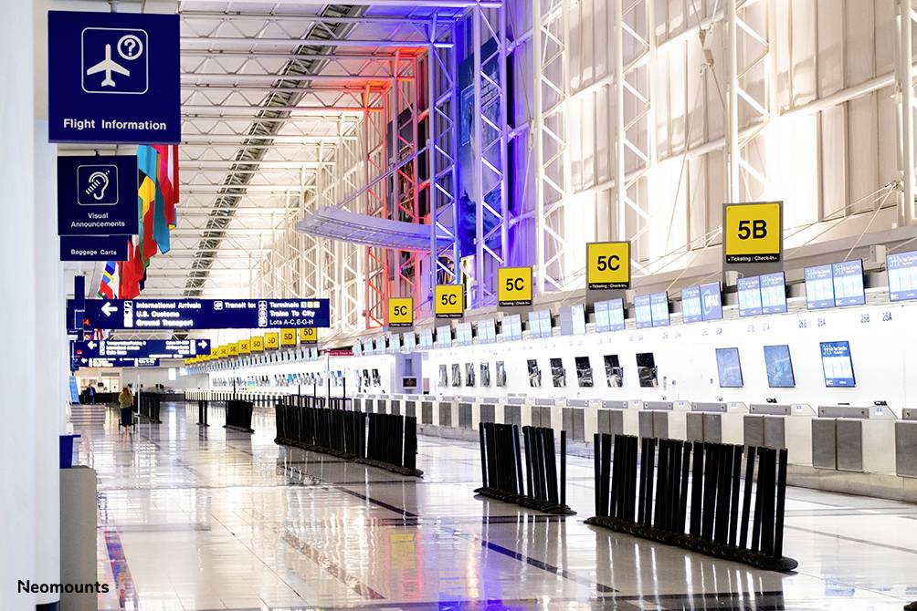 Ein leerer Flughafen-Check-in-Bereich mit beleuchteten Schaltern, Bildschirmen und Wegweisern für Fluginformationen.
