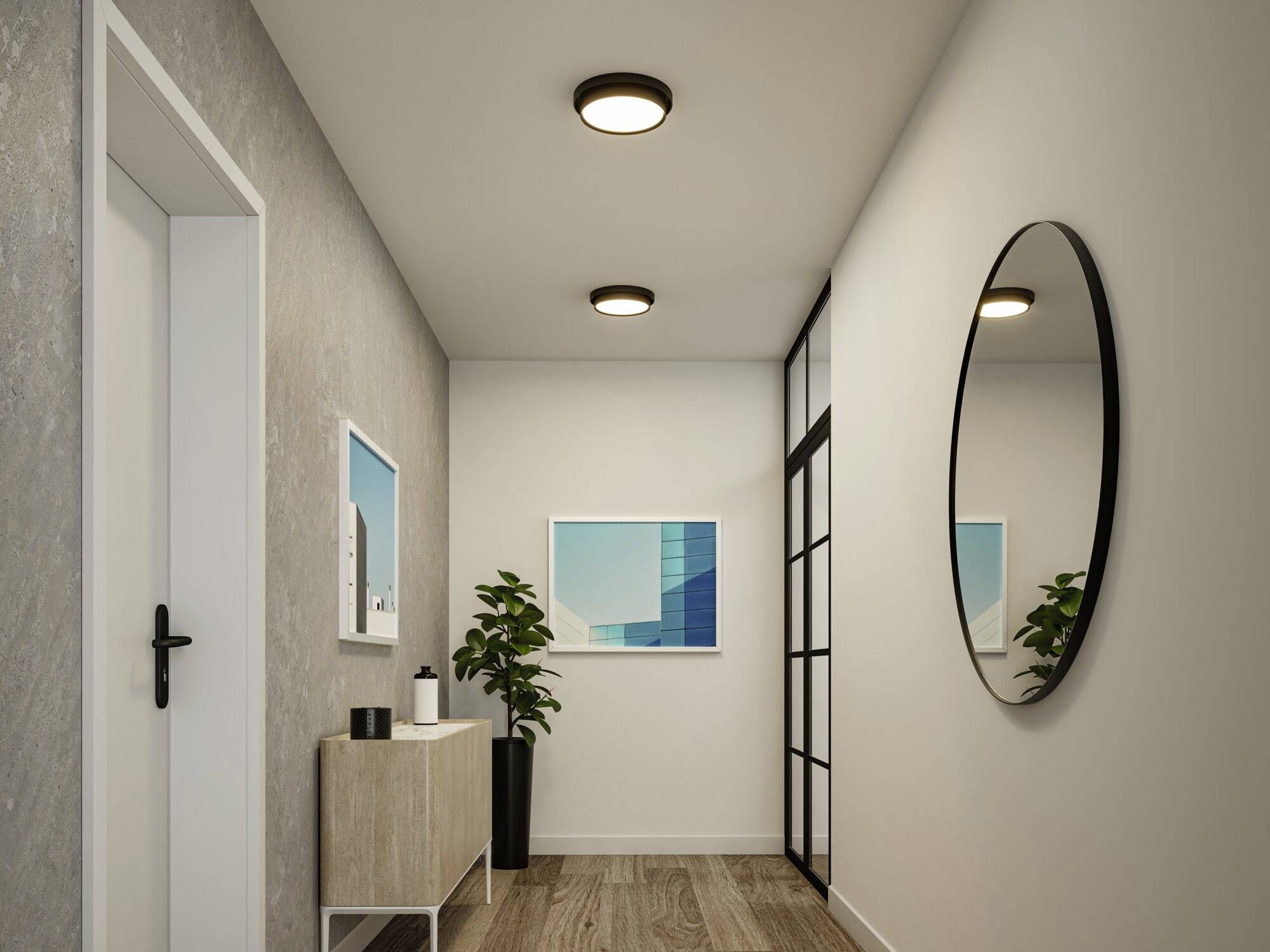 Ein modern eingerichteter Flur mit Holzfußboden, runder Wandspiegel, Sideboard und Pflanzen. Zwei Bilder hängen an der Wand.