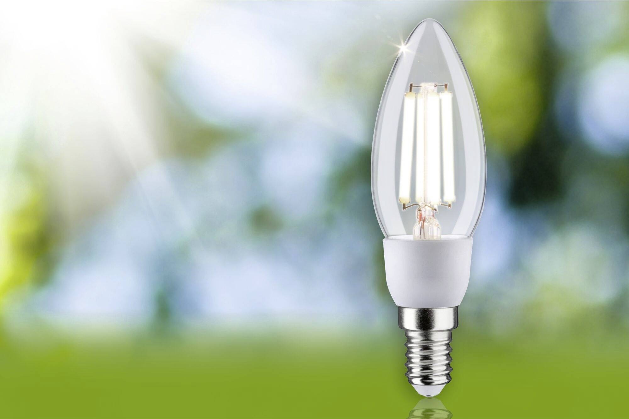 Eine leuchtende LED-Lampe vor einem unscharfen, hellen Hintergrund mit Sonnenstrahlen, symbolisiert Energieeffizienz.