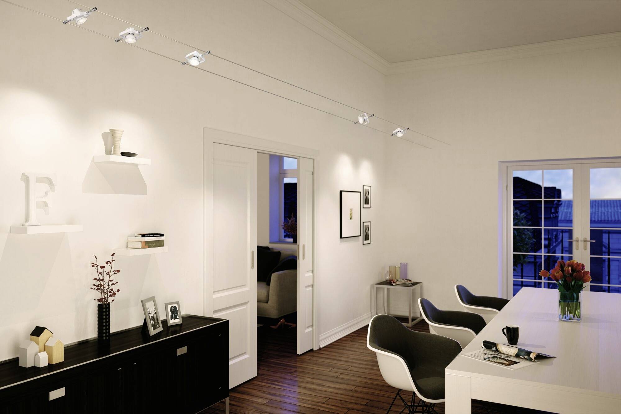 Modernes Wohnzimmer mit hellem Holzfußboden, weißen Wänden und stimmungsvoller Beleuchtung. Ein Esstisch mit Stühlen steht im Vordergrund.