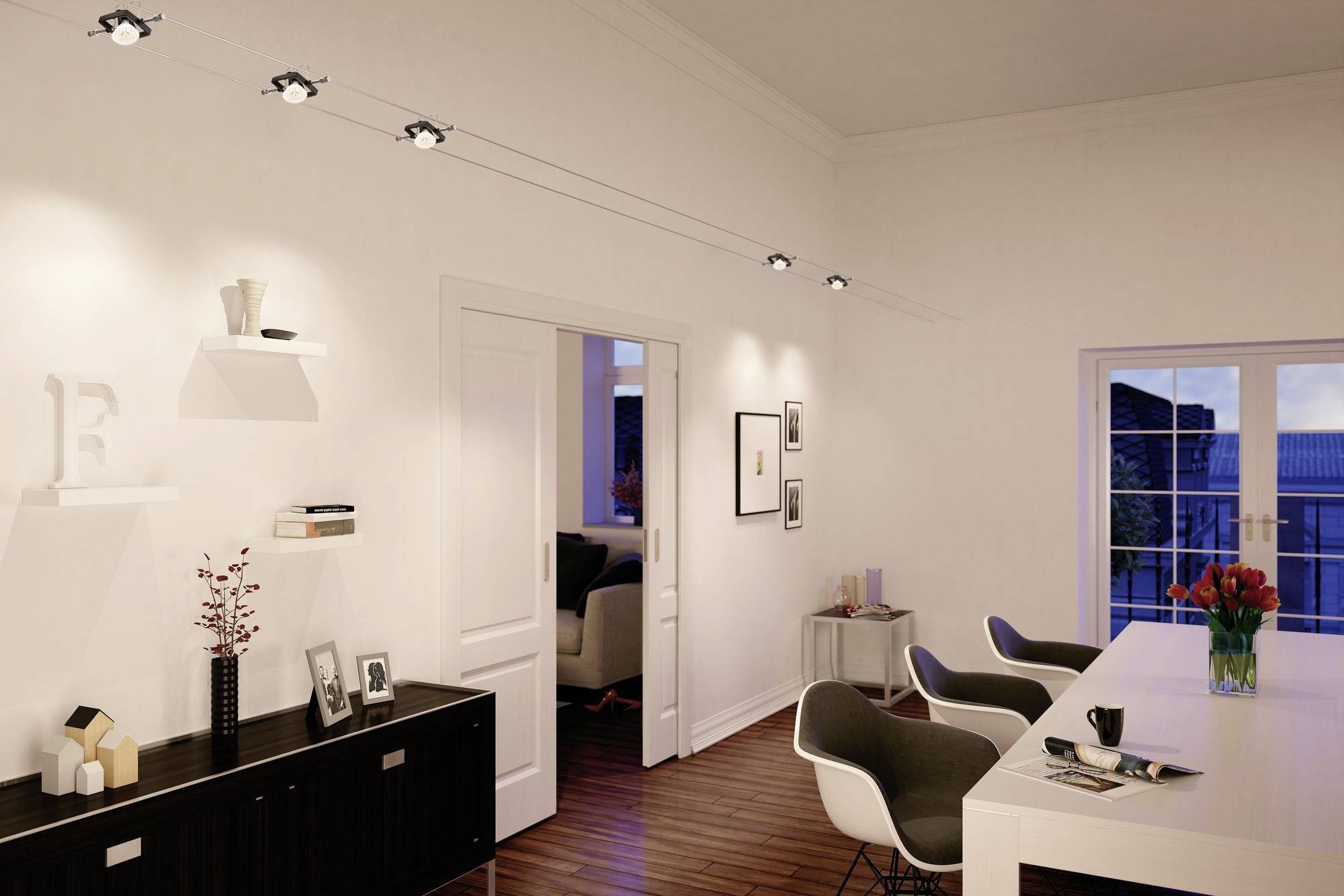 Moderner Wohnraum mit weißer Wand, eleganten Möbeln und stilvoller Beleuchtung. Durch die Fenster ist ein Abendhimmel sichtbar.