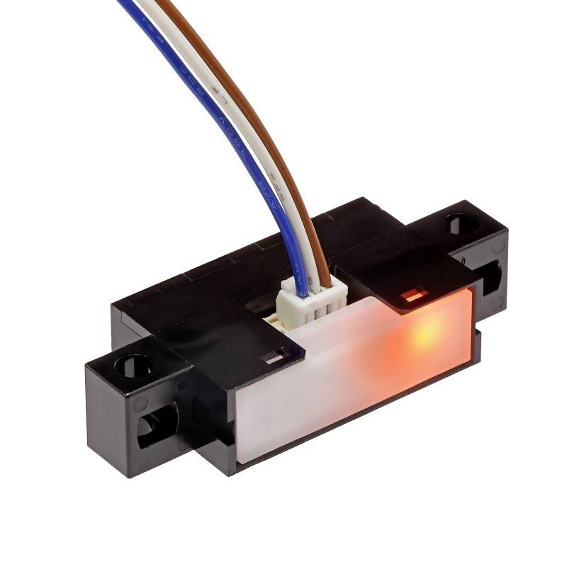 Ein optischer Sensor mit schwarzem Gehäuse, weißen, braunen und blauen Drähten, zeigt rot beleuchtetes Element an der Vorderseite.