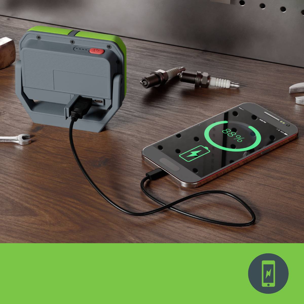 Smartphone wird mit einem tragbaren Ladegerät aufgeladen, Akku bei 85%. Funkenstecker und andere Werkzeuge im Hintergrund.