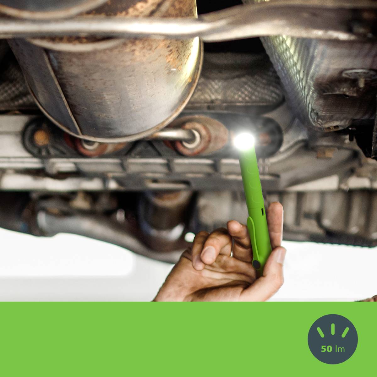 Mechaniker untersucht den Unterboden eines Autos mit einer kleinen Taschenlampe.