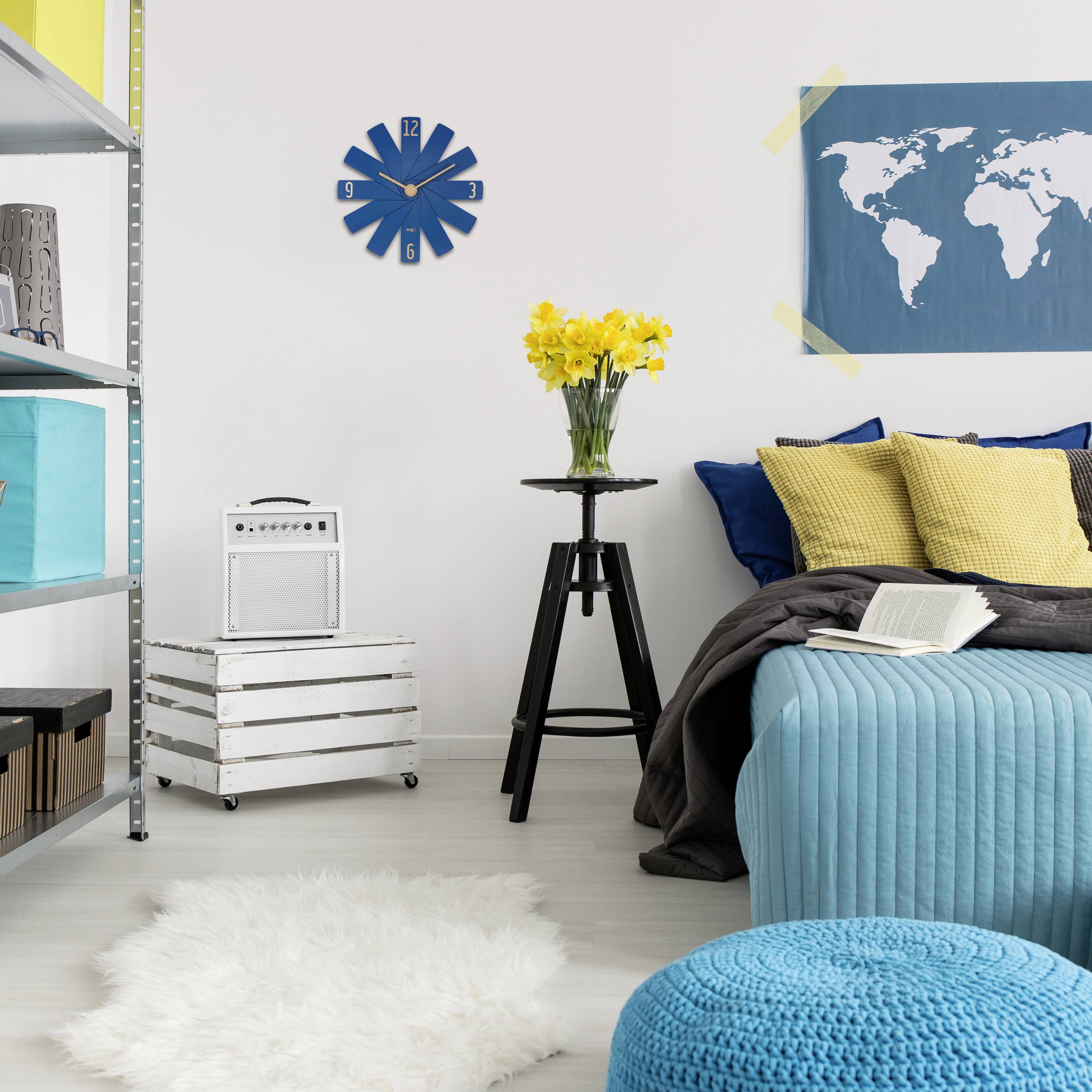 Wohnzimmer mit modernem Stil: Blauer globusförmiger Hocker, gelbe Blumen auf einem Stativ, Weltkarte an der Wand, blaues Sofa.