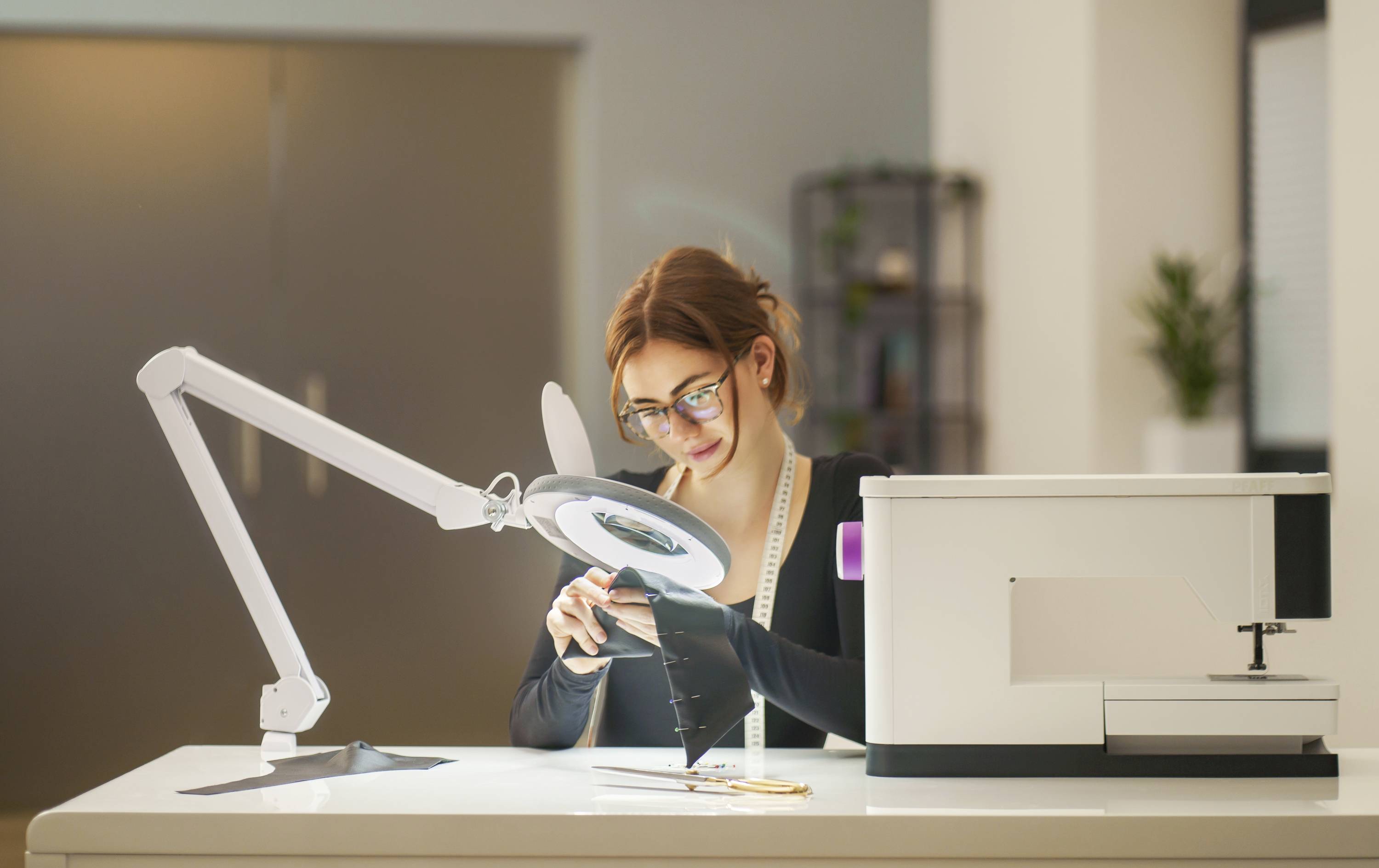 Eine Frau arbeitet konzentriert an einem Projekt in einem modernen Büro, umgeben von technischen Geräten und Lampen.