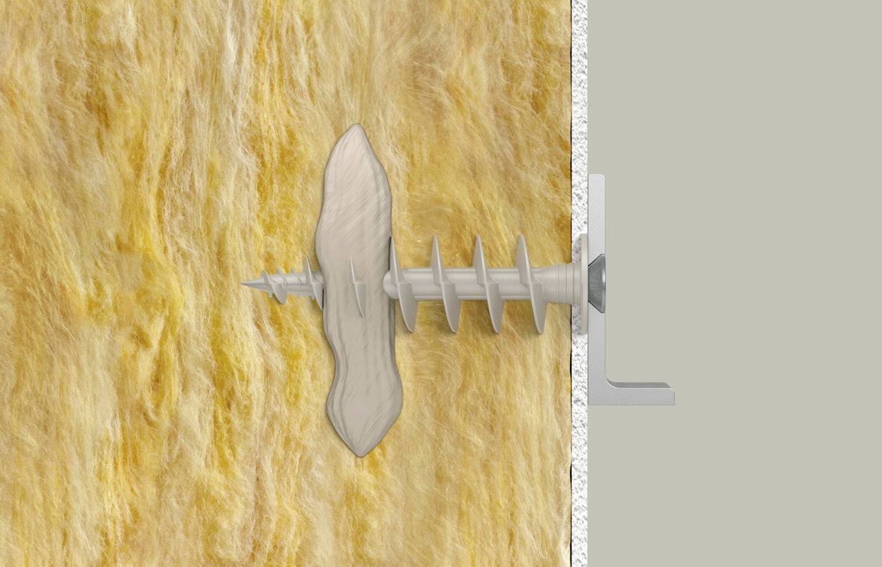 Eine Gipskartondübel wird in eine gelbe Dämmstoffplatte an der Wand verschraubt.