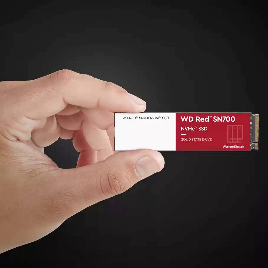 Eine Hand hält eine WD RED SN700 NVMe SSD, ein Speichermedium mit rotem Etikett, das für hohe Geschwindigkeit und Leistung steht.
