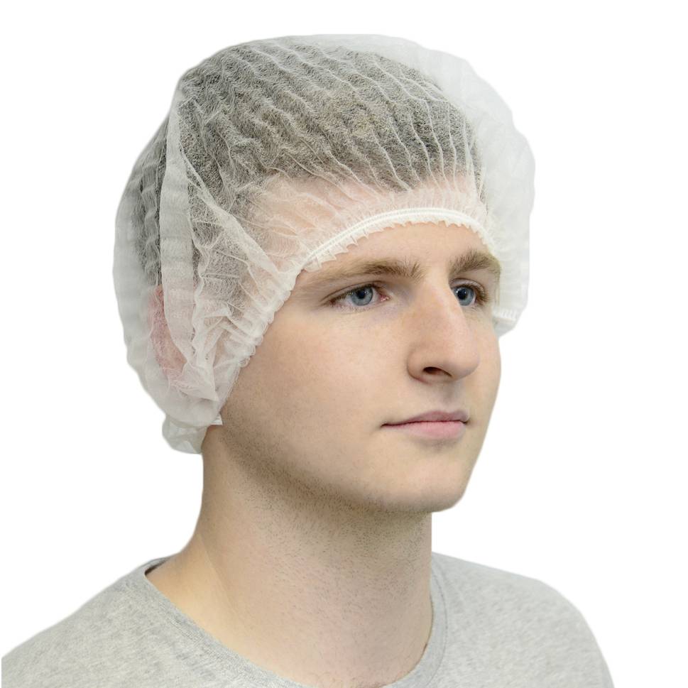 Person trägt eine weiße Haube. Männliches Gesicht, neutraler Ausdruck. Hintergrund neutral, Fokus auf Schutzkleidung.