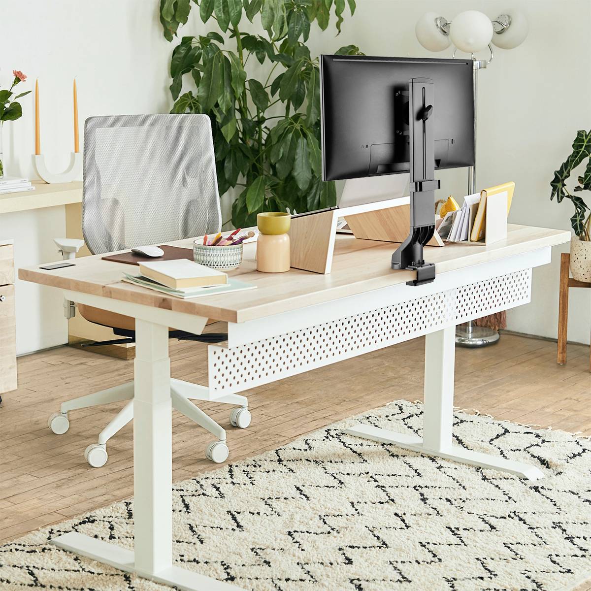 Ein moderner Arbeitsplatz mit einem Schreibtisch, Computerbildschirm, Bürostuhl und Pflanzen im Hintergrund. Helle, minimalistische Einrichtung.