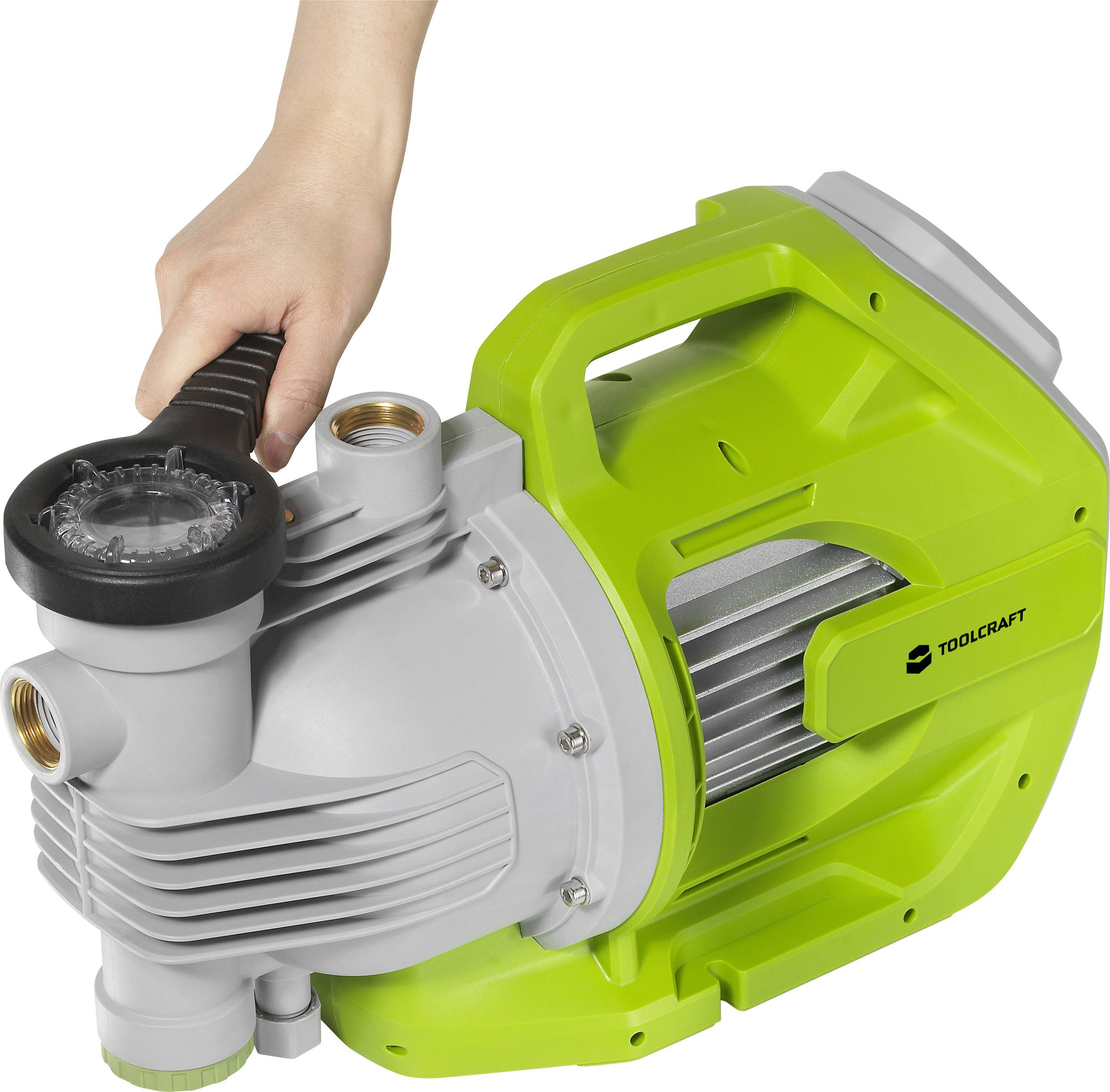 Eine Hand hält eine grüne Wasserpumpe von TOOLCRAFT mit Griff, geeignet für Garten- oder Hauswasserarbeiten.