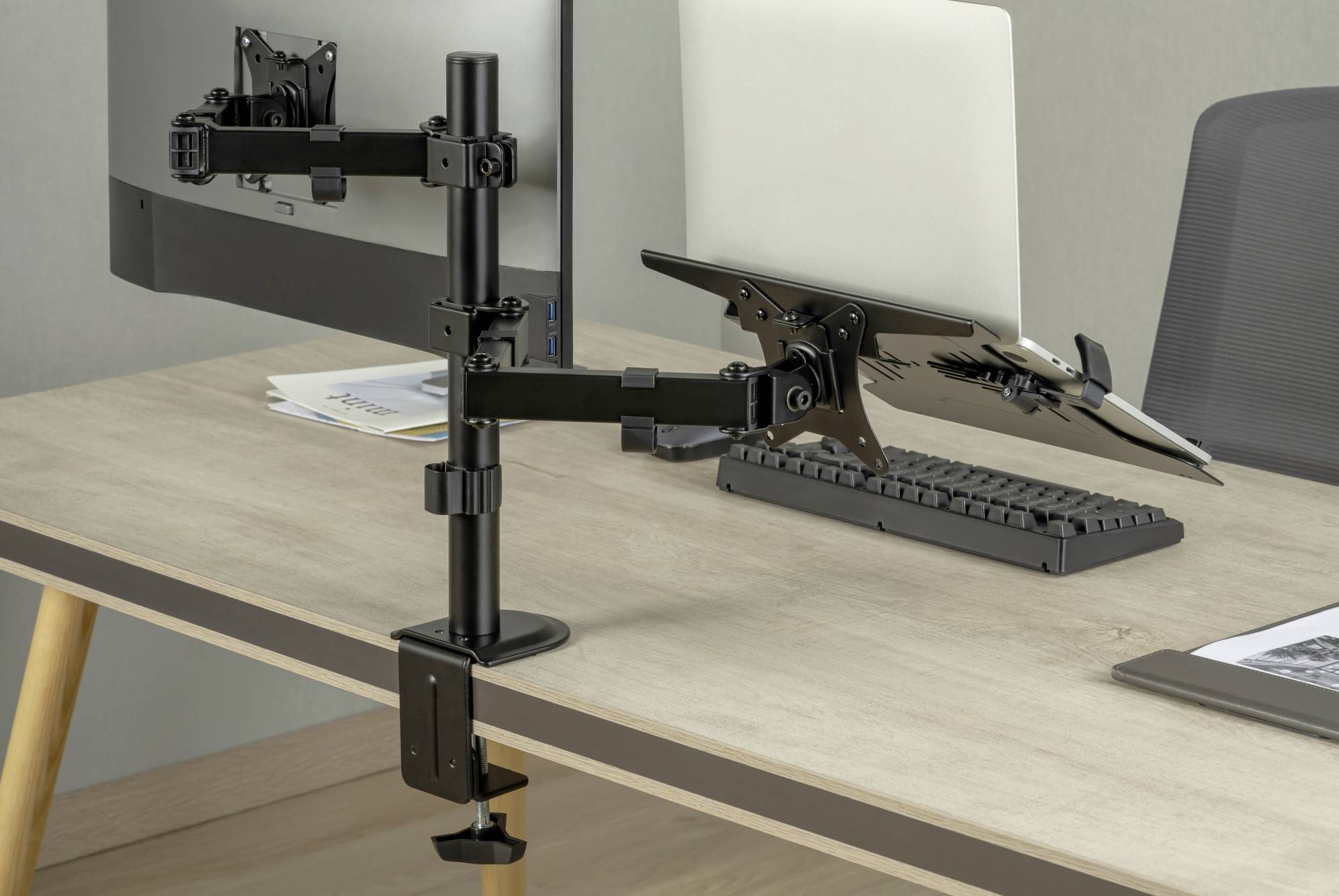 Ein Schreibtisch mit zwei Monitoren an Halterungen. Einer zeigt ein Dokument, der andere ist leer. Eine Tastatur liegt dazwischen.