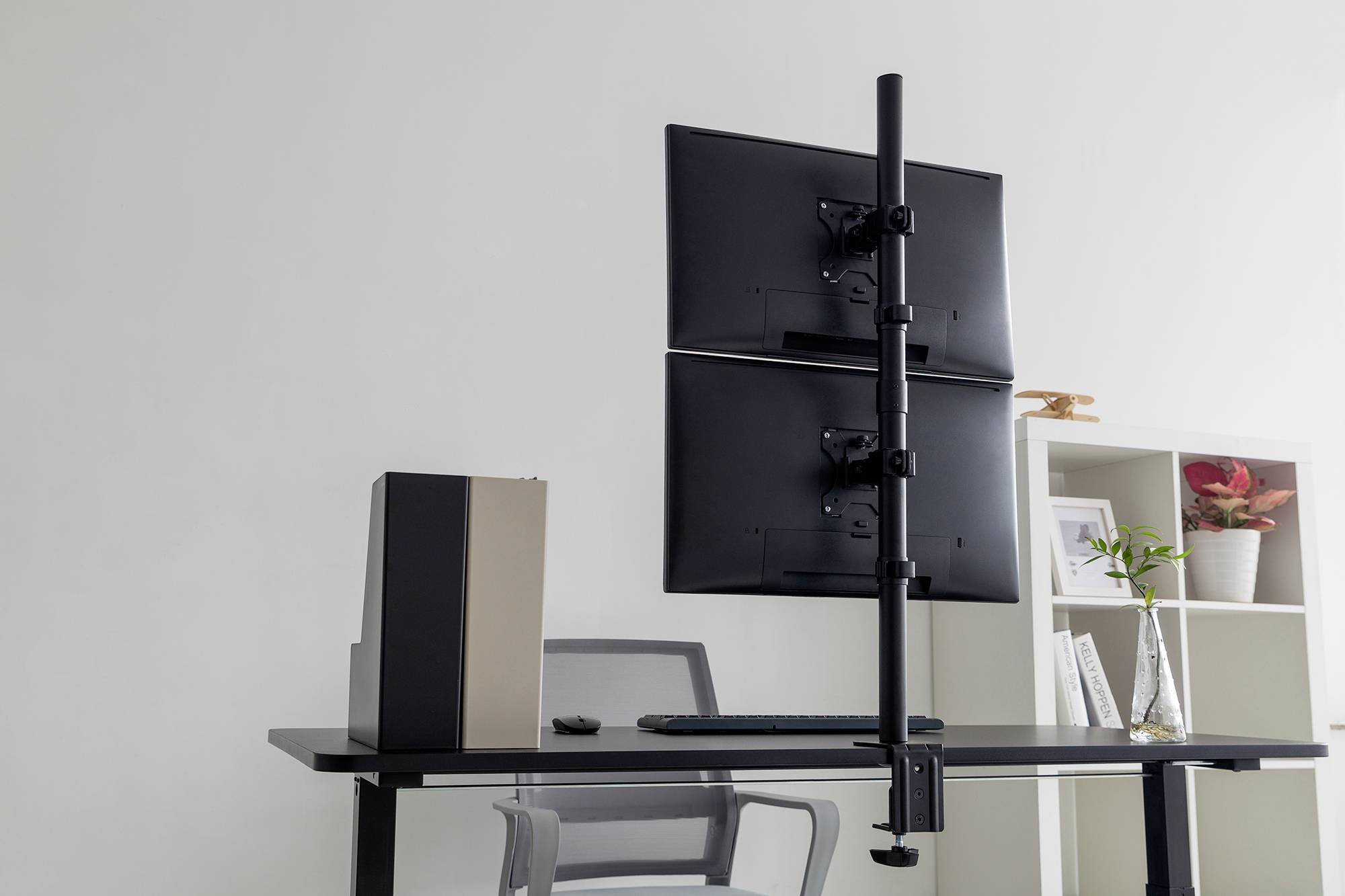 Moderner Schreibtisch mit zwei Monitoren in vertikaler Halterung, Tastatur, kreativem Aktenschrank und Regal mit Pflanzen im Hintergrund.