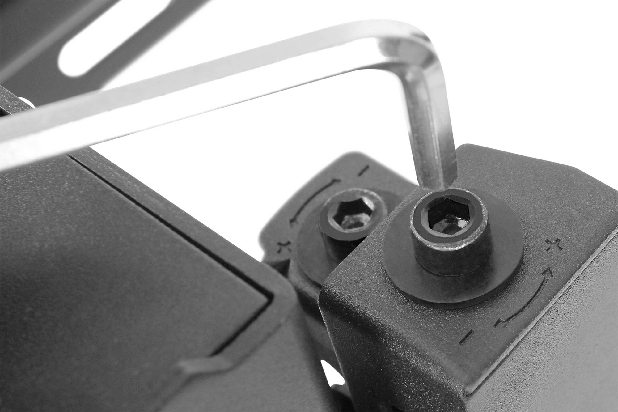 Nahaufnahme eines Sechskantschlüssels, der eine Schraube in einem mechanischen Gerät festzieht, auf einem weißen Hintergrund.