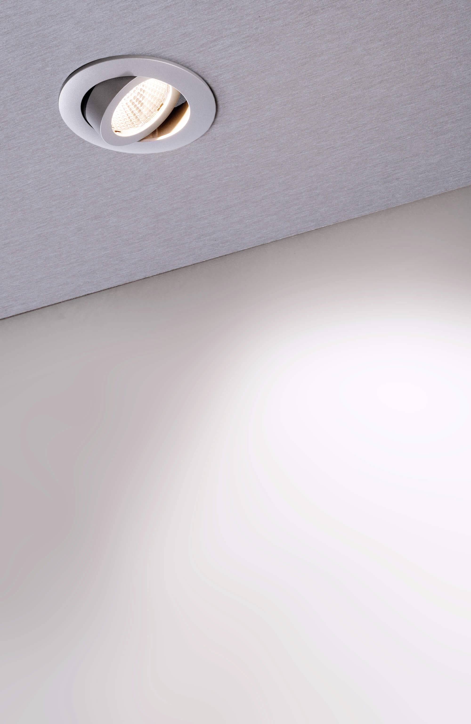 Eine einzelne Einbaulampe an der Decke leuchtet einen Bereich des Raums aus, der in hellem Licht erstrahlt.