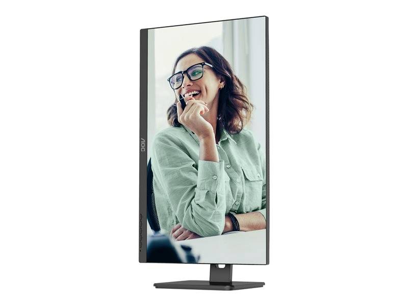 Eine Frau mit Brille lächelt und blickt nach links, während sie einen Stift hält. Der Monitor steht im Hochformat.