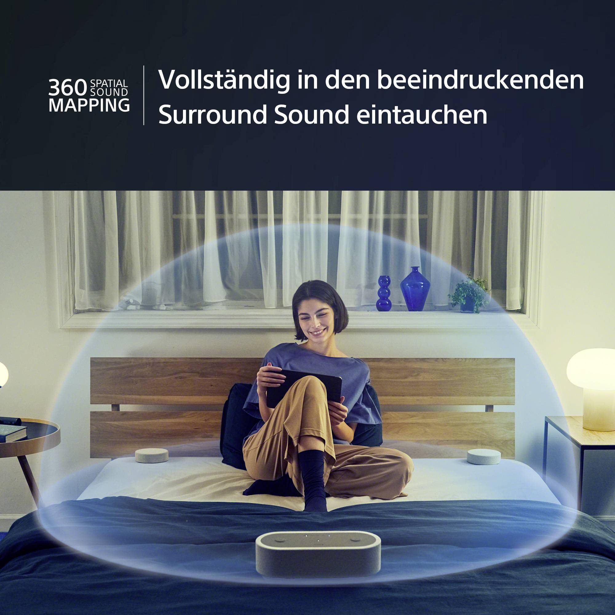 Eine Person sitzt auf einem Bett und verwendet ein Tablet. Um sie herum ist eine Visualisierung von 360-Grad-Raumklang zu sehen.