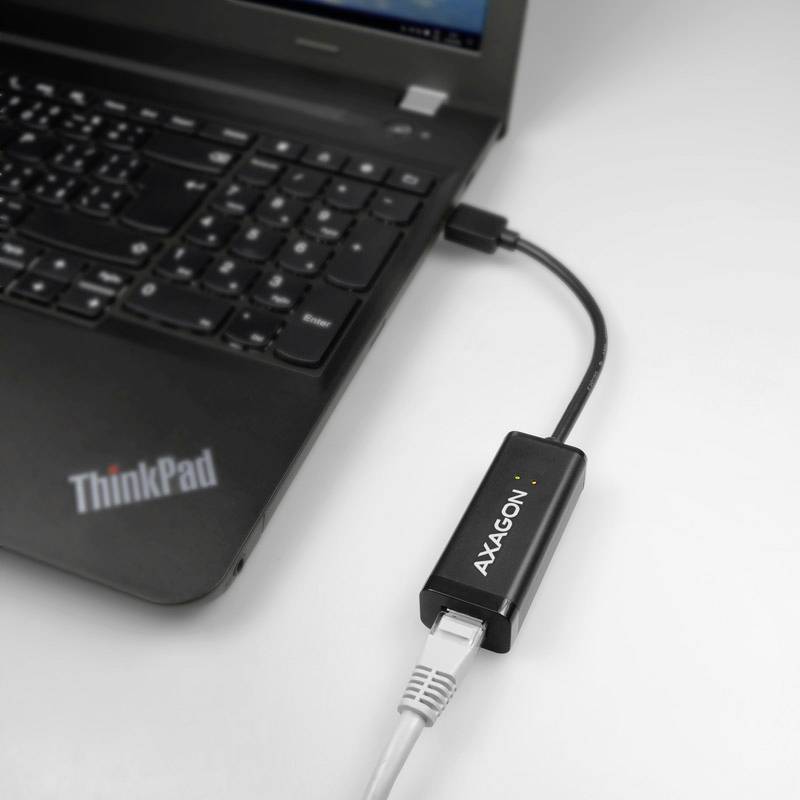 Ein Laptop mit einer angeschlossenen 'AXAGON'-Netzwerkadapter; zeigt Laptop-Verbindung über Ethernet-Kabel.