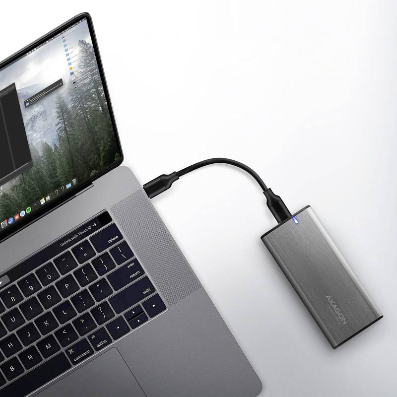 Ein Laptop mit einem angeschlossenen externen silbernen Festplattengehäuse über ein USB-Kabel, betriebsbereit angezeigt durch ein blaues Licht.