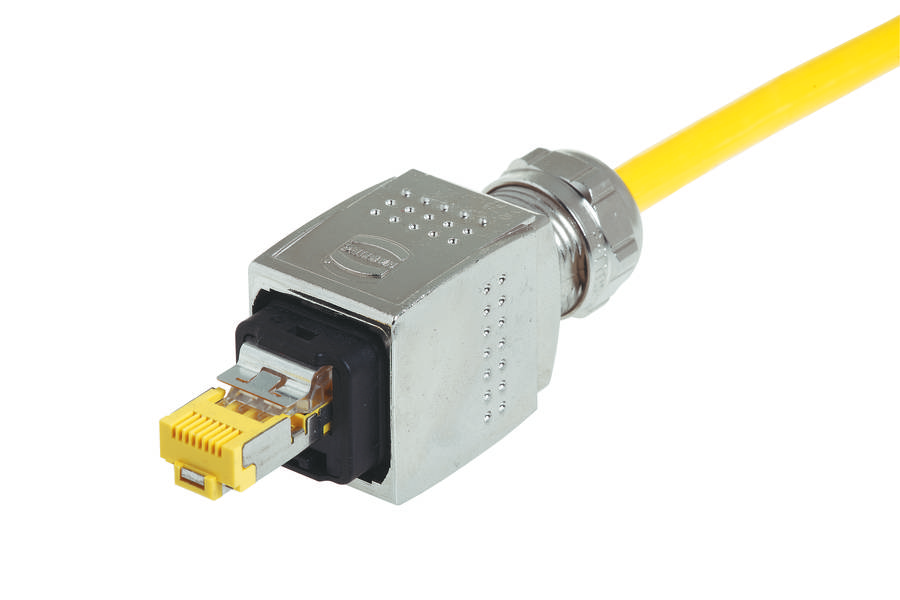 Ein gelbes Netzwerkkabel mit einem metallischen Stecker, der an einem Anschlussgerät befestigt ist, vor weißem Hintergrund.