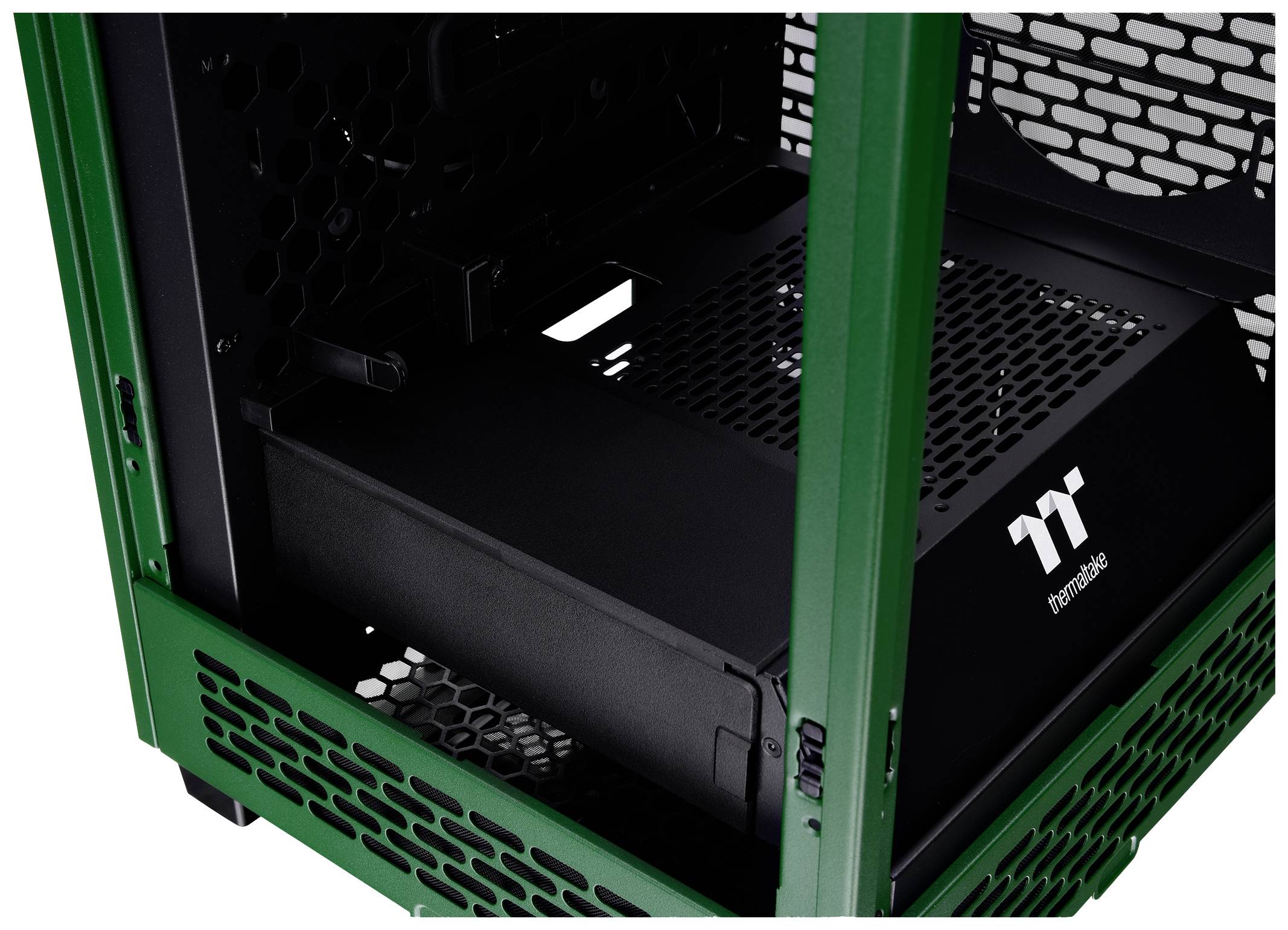 Grünes Computergehäuse im Inneren mit einem schwarzen Netzteil der Marke Thermaltake. Mesh-Design für Belüftung sichtbar.