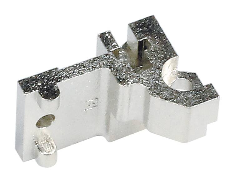Ein kleines, metallisches Bauteil mit zwei Löchern und unregelmäßiger Form, möglicherweise als Verbindungselement oder Halterung genutzt.