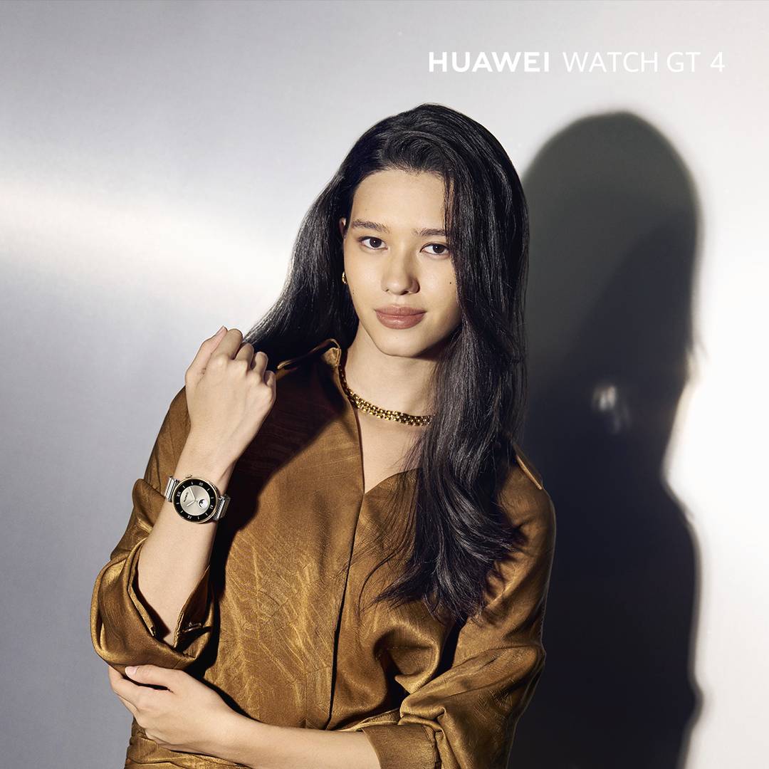 Frau in goldener Bluse trägt eine Armbanduhr, Modell 'Huawei Watch GT 4'. Die Uhr hat ein rundes Zifferblatt mit sichtbarem Armband.