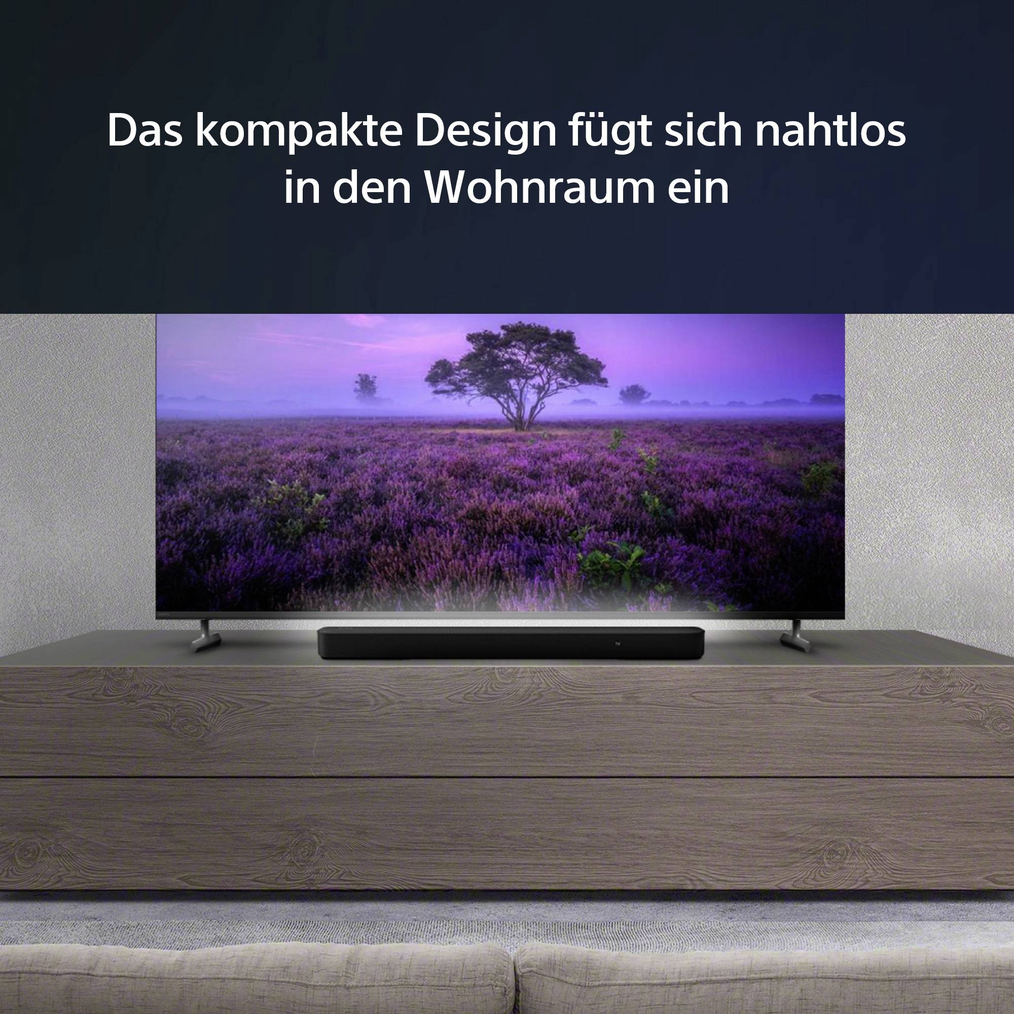 Ein moderner Fernseher steht auf einem Holzschrank. Der Bildschirm zeigt eine lila Landschaft mit einem Baum unter einem violetten Himmel.