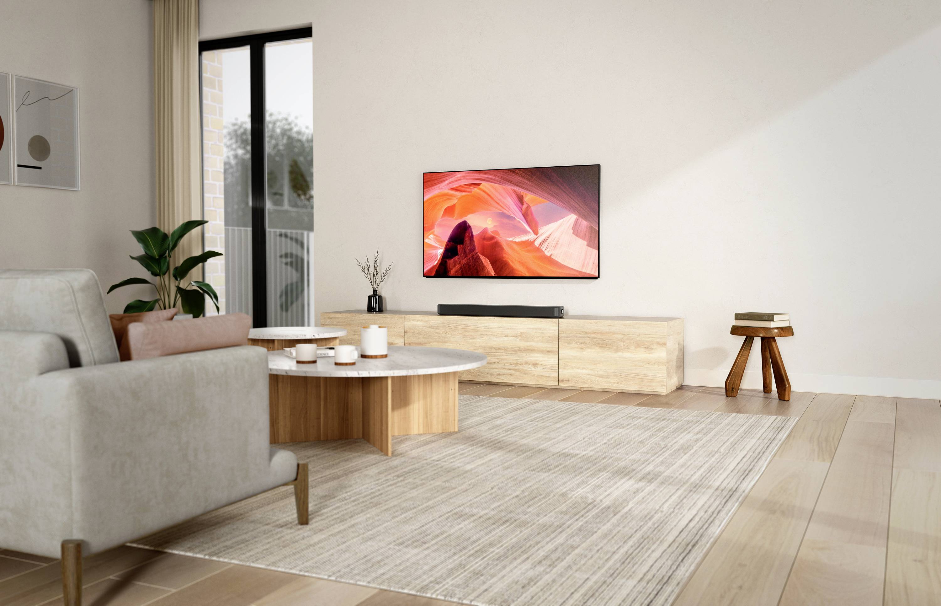 Ein Wohnzimmer mit einem modernen Fernseher, der ein abstraktes Bild zeigt. Ein helles Sofa, Holztisch und Pflanzen dekorieren den Raum.