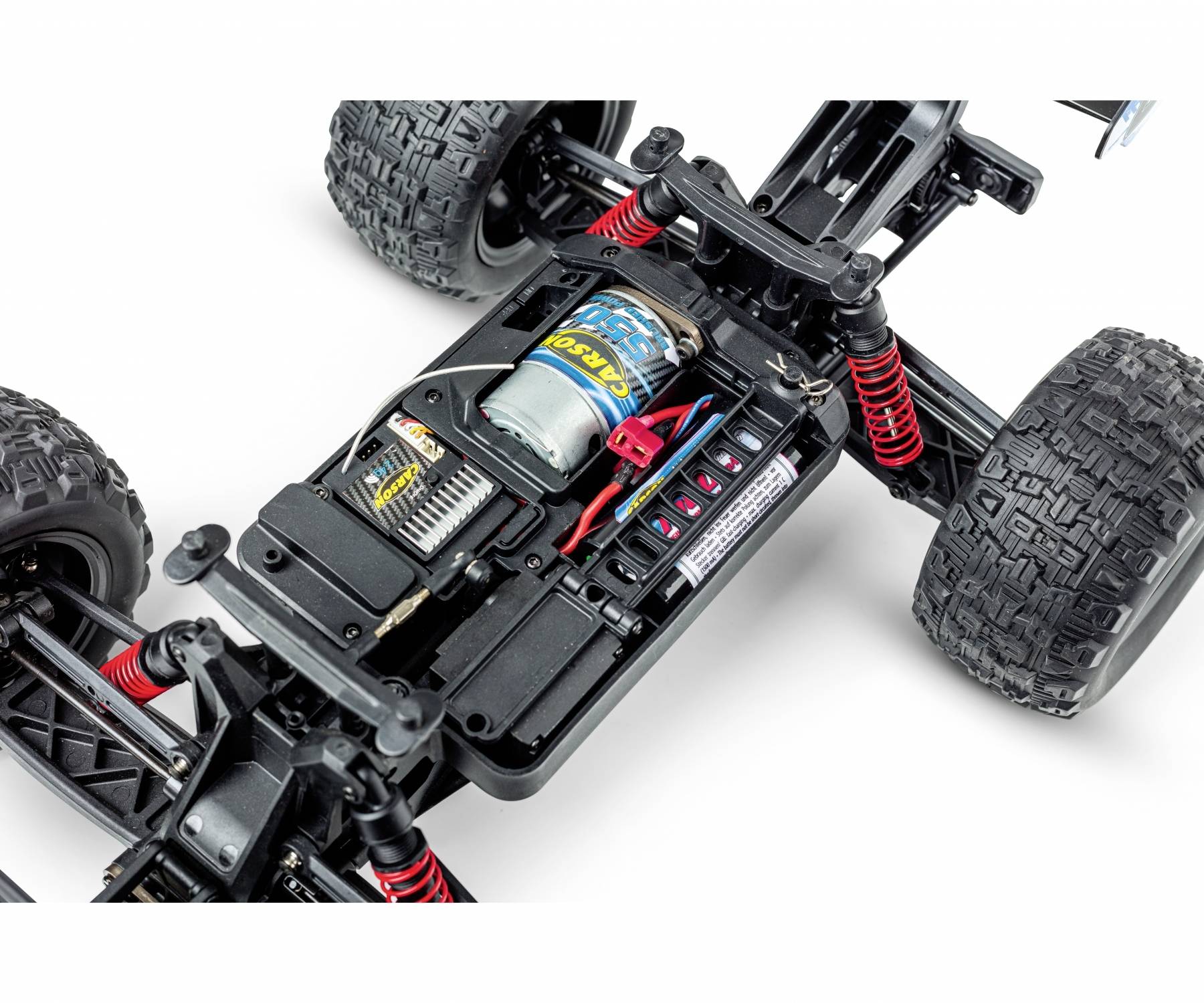 Nahaufnahme eines ferngesteuerten Autos ohne Karosserie, zeigt Motor, Federung und Akkufach. Deutliche Ansicht der technischen Details.